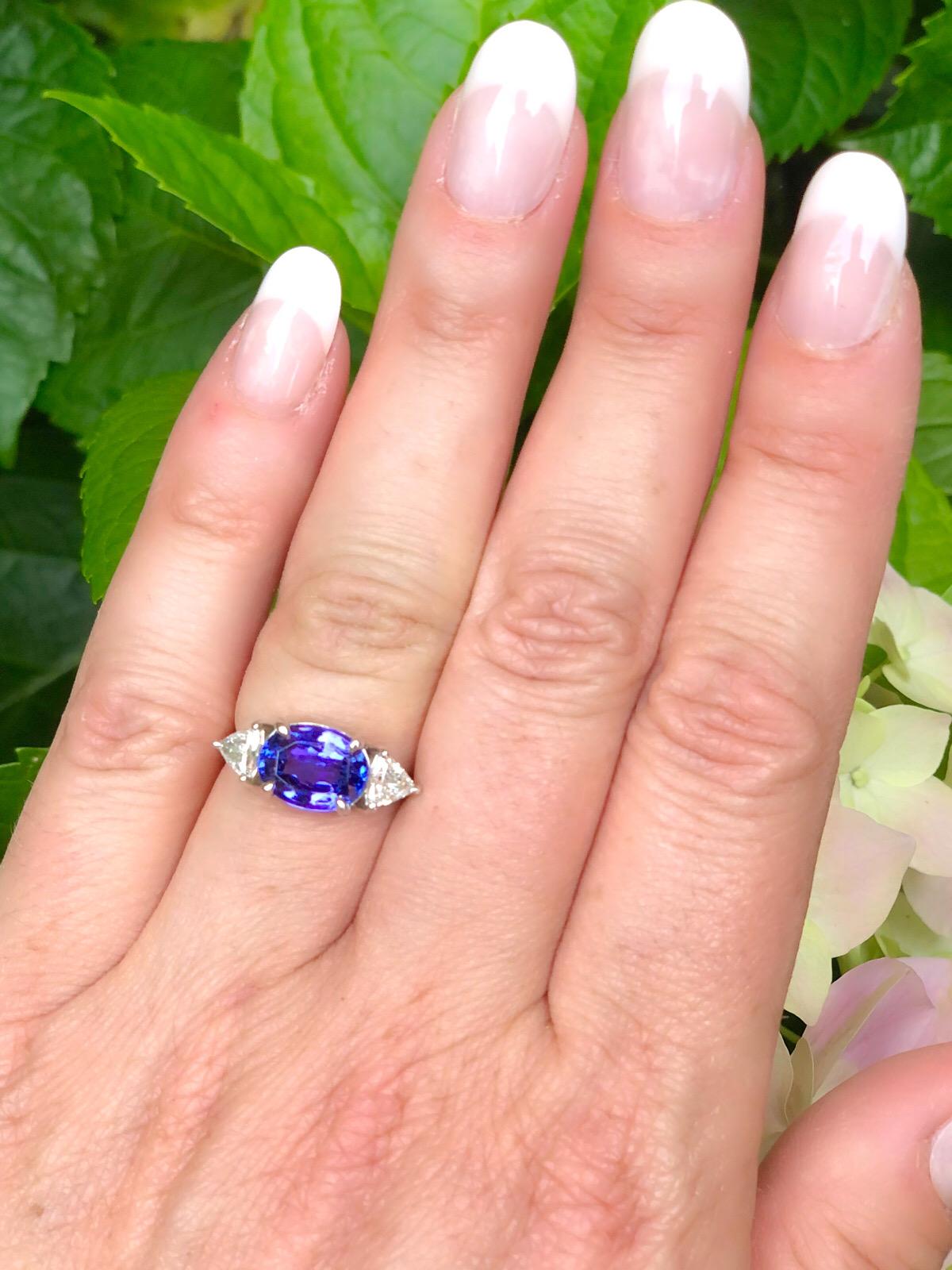 Blending contemporary and classic design, this eye-catching ring features a horizontally-set 3.40- cts. oval tanzanite, set on each side with two triangular-cut diamonds, weighing together approximately 0.55-ct. The 18k white gold ring weighs 3.8