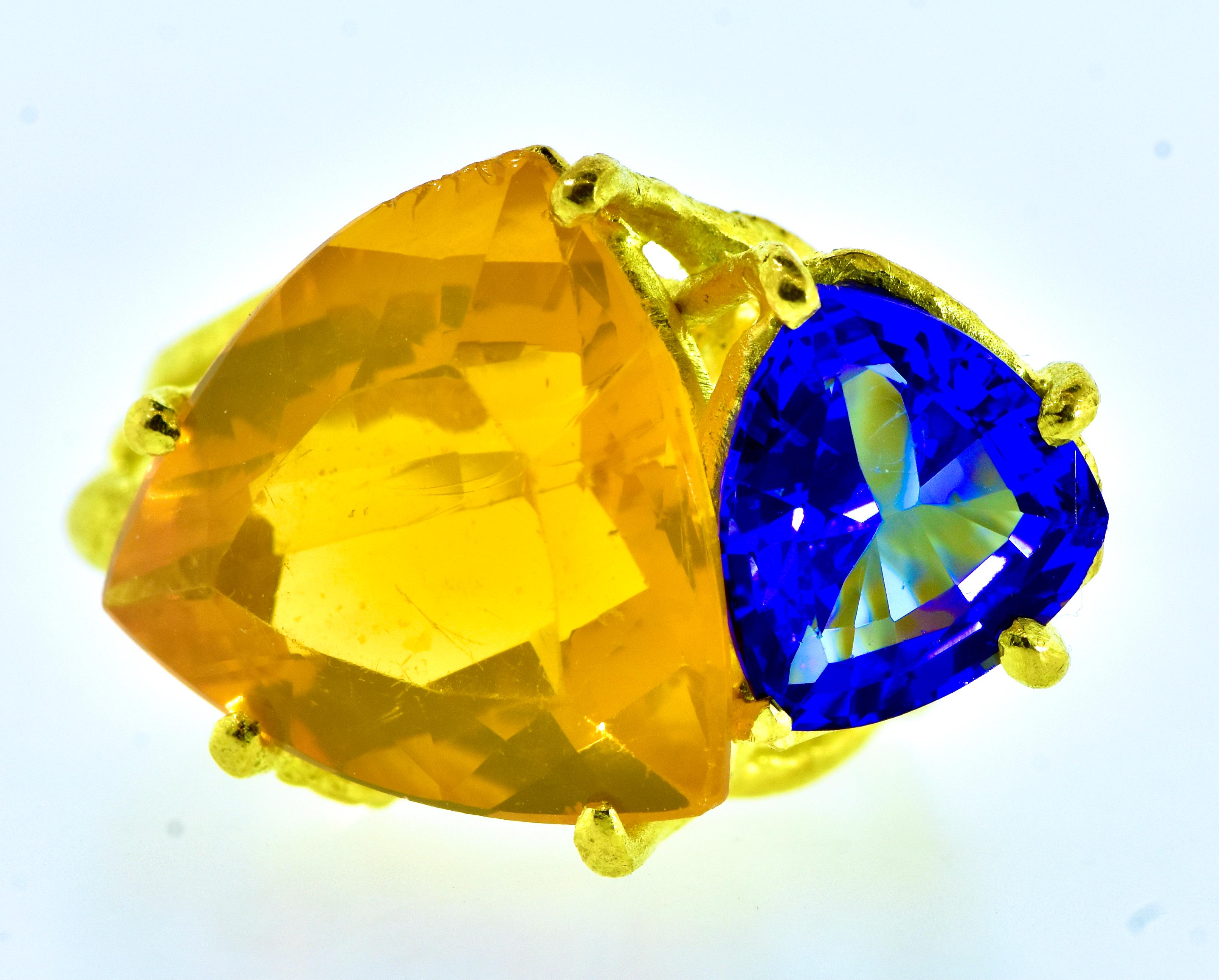Fine blue Tanzanite and  an orange fire opal ring set into a modernist 18K yellow gold ring.  The fine medium blue, with a hint of violet, and very clean Tanzanite weighs an estimated 1.25 cts. and the light to medium orange,  bright and clean