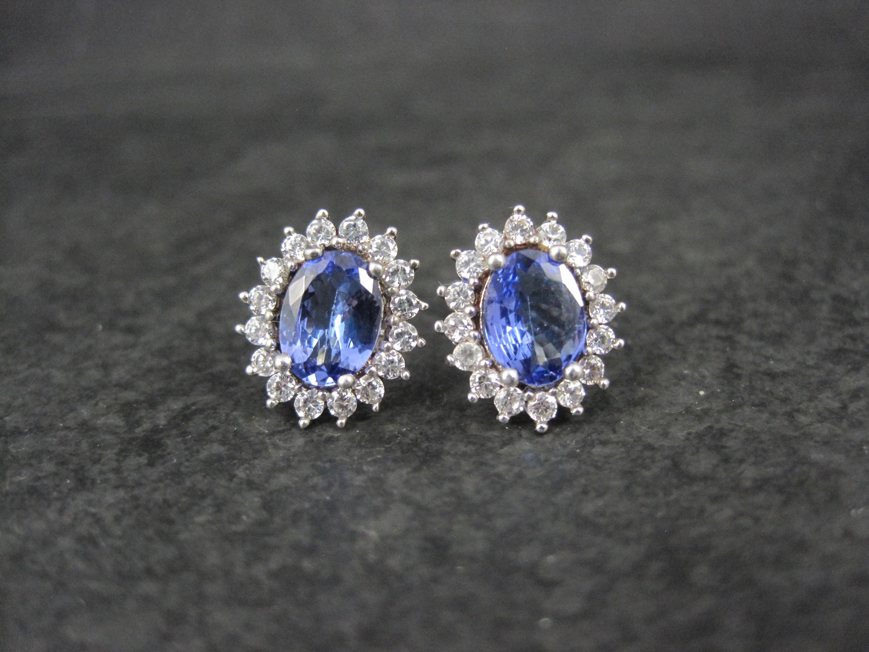 These gorgeous stud earrings are sterling silver.
They feature 6x8mm oval cut tanzanites surrounded by a halo of  round cut 2mm white spinel.

Measurements: 7/16 by 9/16 of an inch

Originally from Kay Jewelers these earrings retailed for over