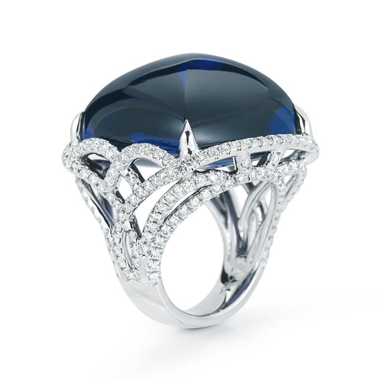 TANZANITE CABOCHON AND DIAMOND RING This captivating sugarloaf Tanzanite of magnificent color is embraced by a delicate lattice of diamonds in a pave setting Item: # 01905 Metal: 18k W Lab: Gia Color Weight: 71.70 ct. Diamond Weight: 2.62 ct.
