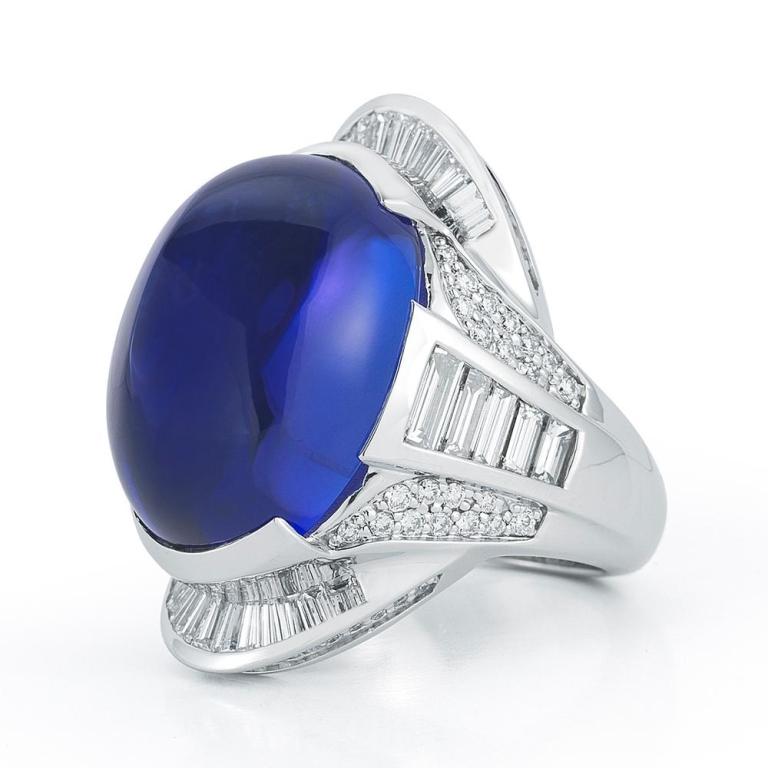 TANZANITE CABOCHON AND DIAMOND RING Dramatic oval cabochon Tanzanite with a striking arrangement of diamond baguettes. Item: # 01670 Metal: 18k W Color Weight: 33.32 ct. Diamond Weight: 2.71 ct.

