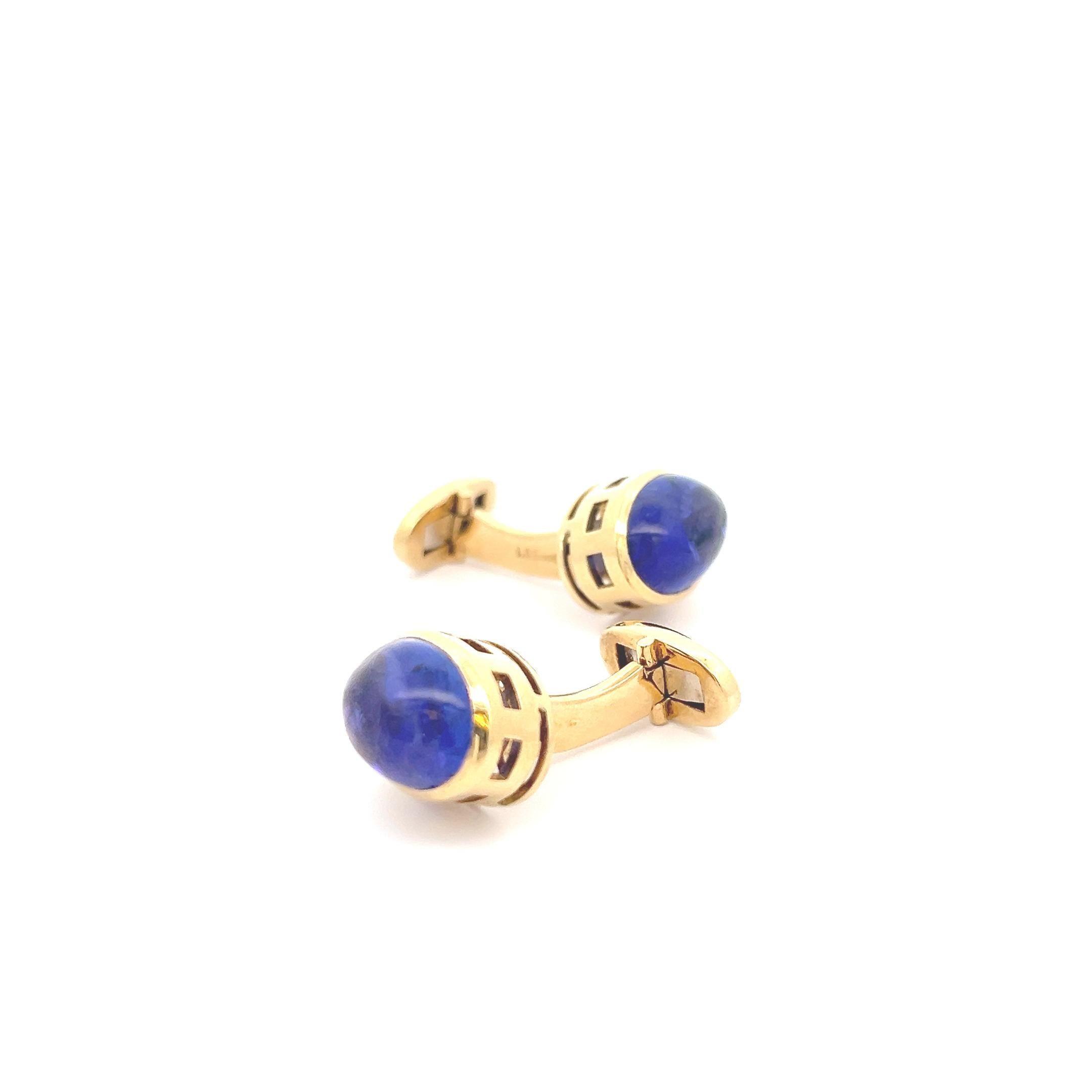 Indulge in the epitome of luxury and sophistication with these exquisite 18k yellow gold cufflinks, adorned with a magnificent display of tanzanite cabochons and blue sapphire baguettes.
At the forefront of each cufflink, gleaming oval tanzanite