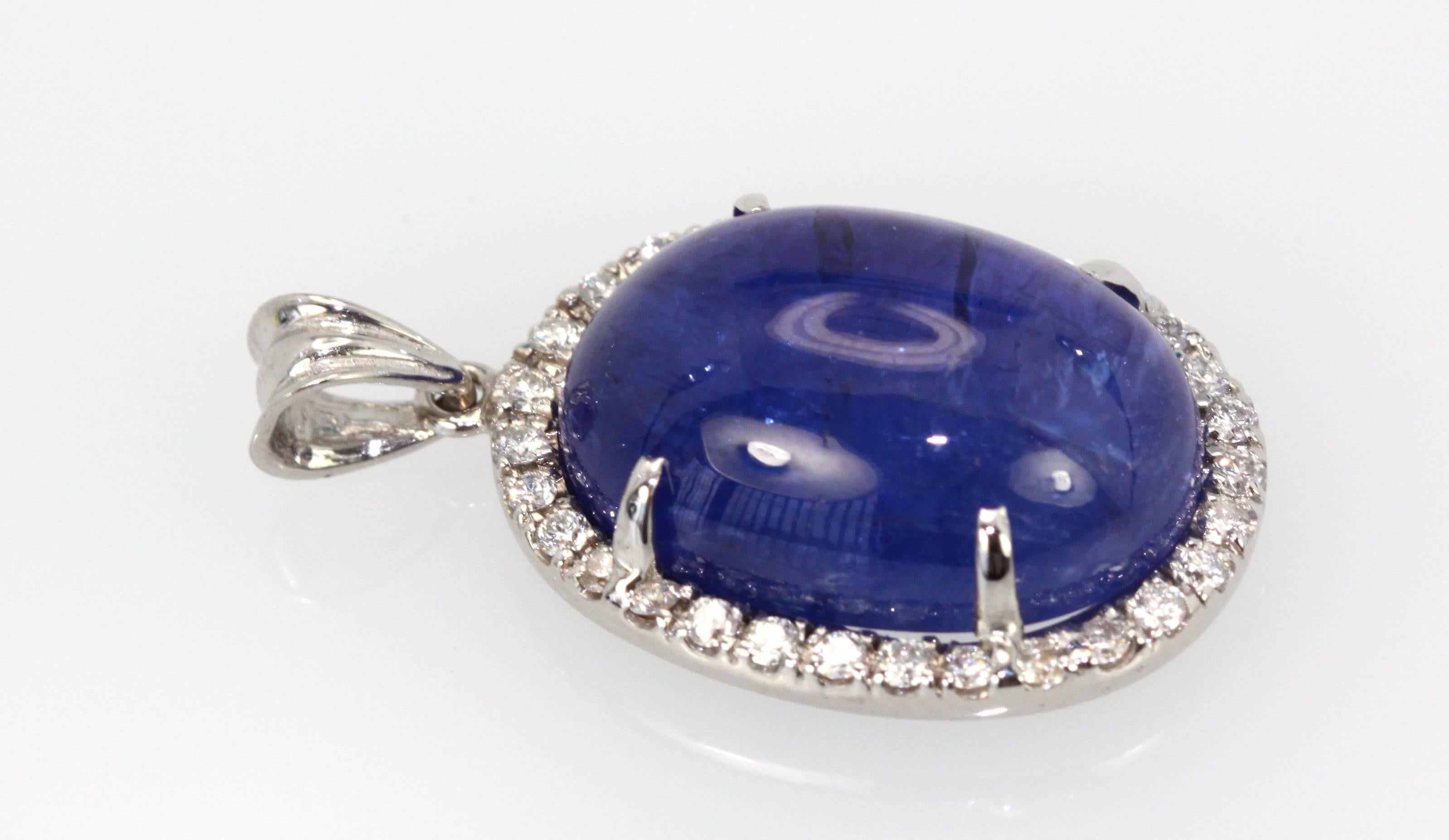 This Tanzanite Cabochon Pendant with a Diamond surround is done in 18K White Gold and is brand new and never been worn.  This tanzanite is a gorgeous shade of blue with nice metrics and it is large 21 Carats with a Diamond Border of .50 Carats of