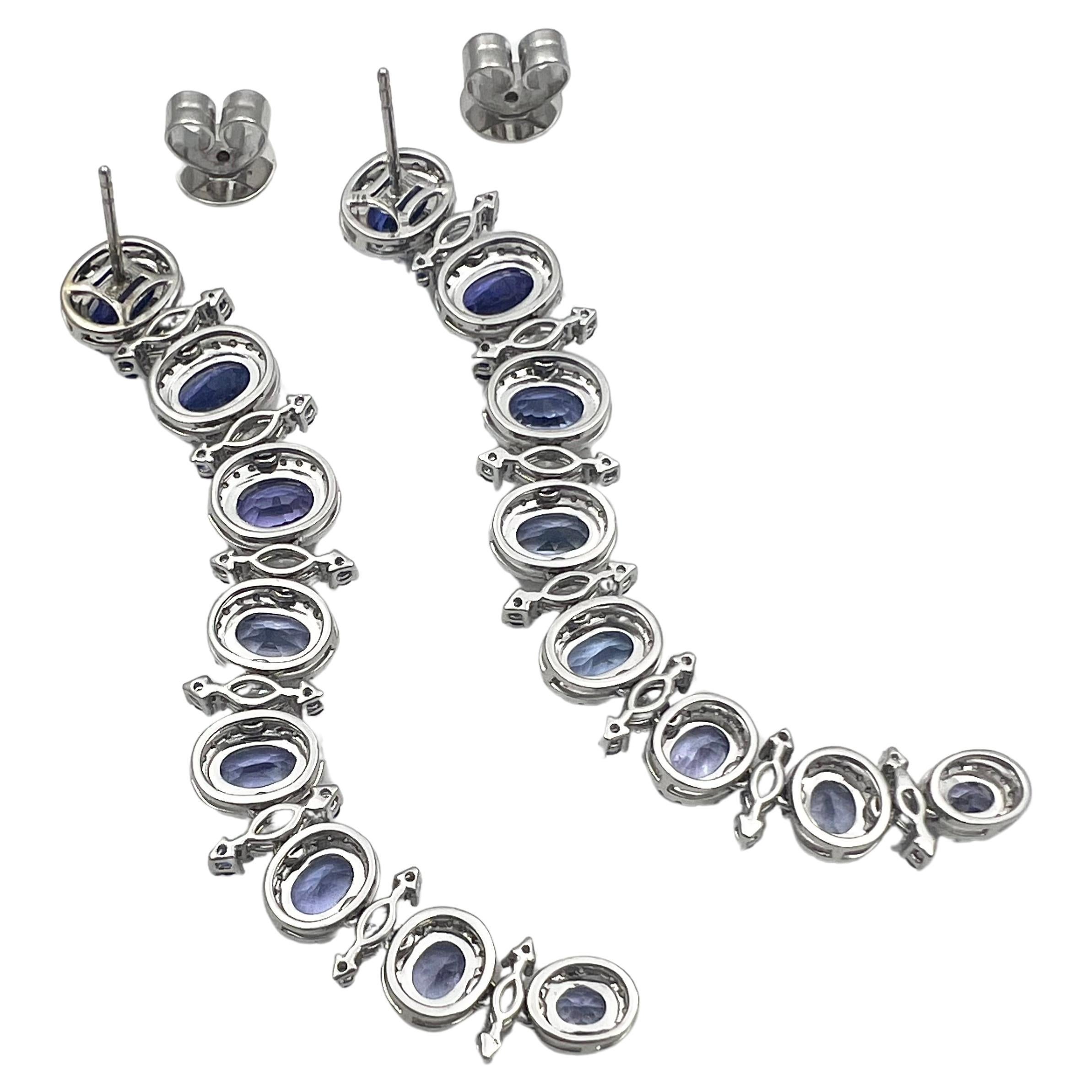 Tapered long earrings 18k white gold set with tanzanite and diamonds.  Measuring 2.75 inches in length. Having sixteen vibrant violet-blue, oval faceted, natural tanzanite surrounded by round brilliant cut diamonds.  Set in between each are fourteen
