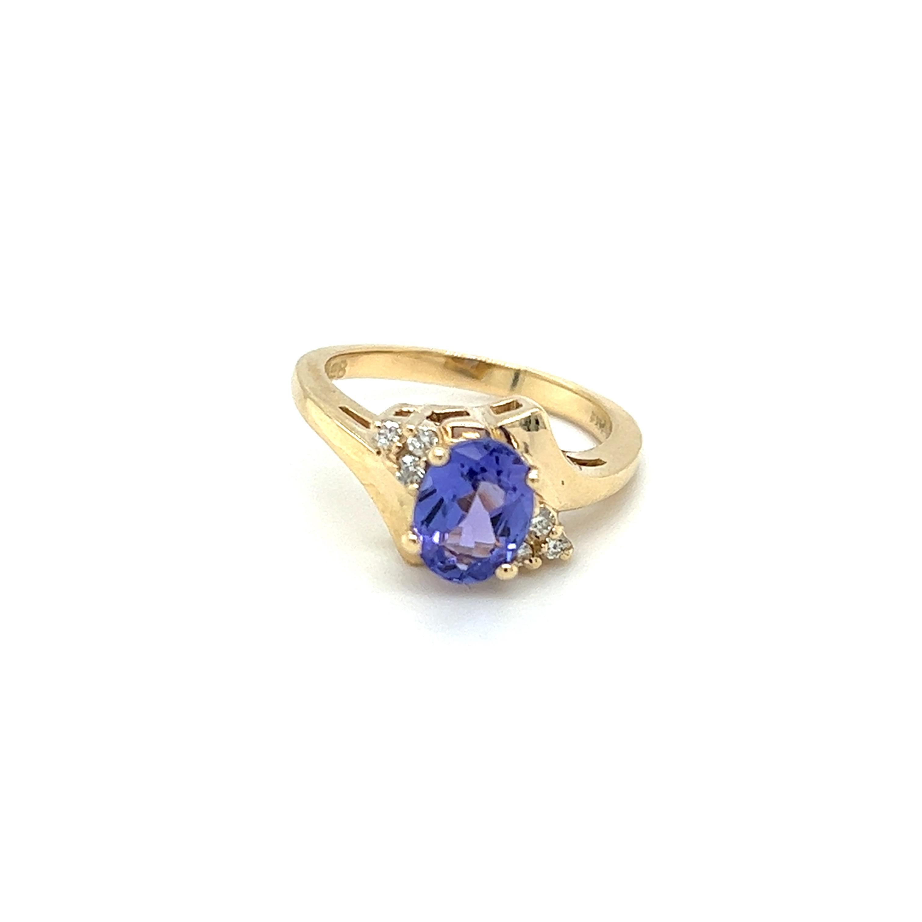 One 14 karat yellow gold (stamped 14K) bypass design ring, set with one (1) 8x6mm oval tanzanite and six (6) brilliant cut diamonds, approximately 0.12 carat total weight with matching I/J color and SI1 clarity. The ring is a finger size 6.25 and