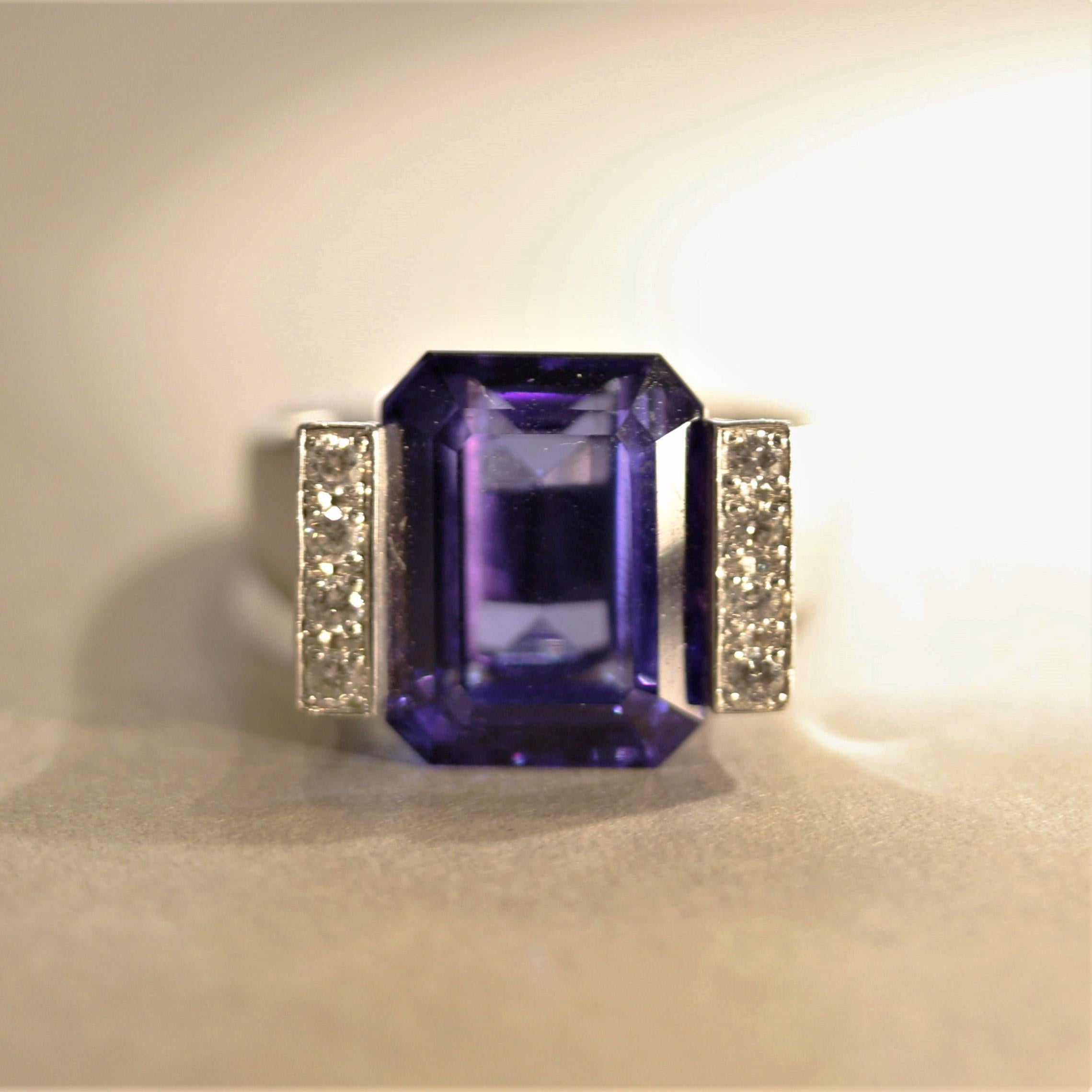 A unique and modern design, this ring features a 10.79 carat gem tanzanite with exceptional color and clarity. It is an emerald-cut with an intense purplish-blue color that can rival the finest sapphires. It is accented by two rows of round