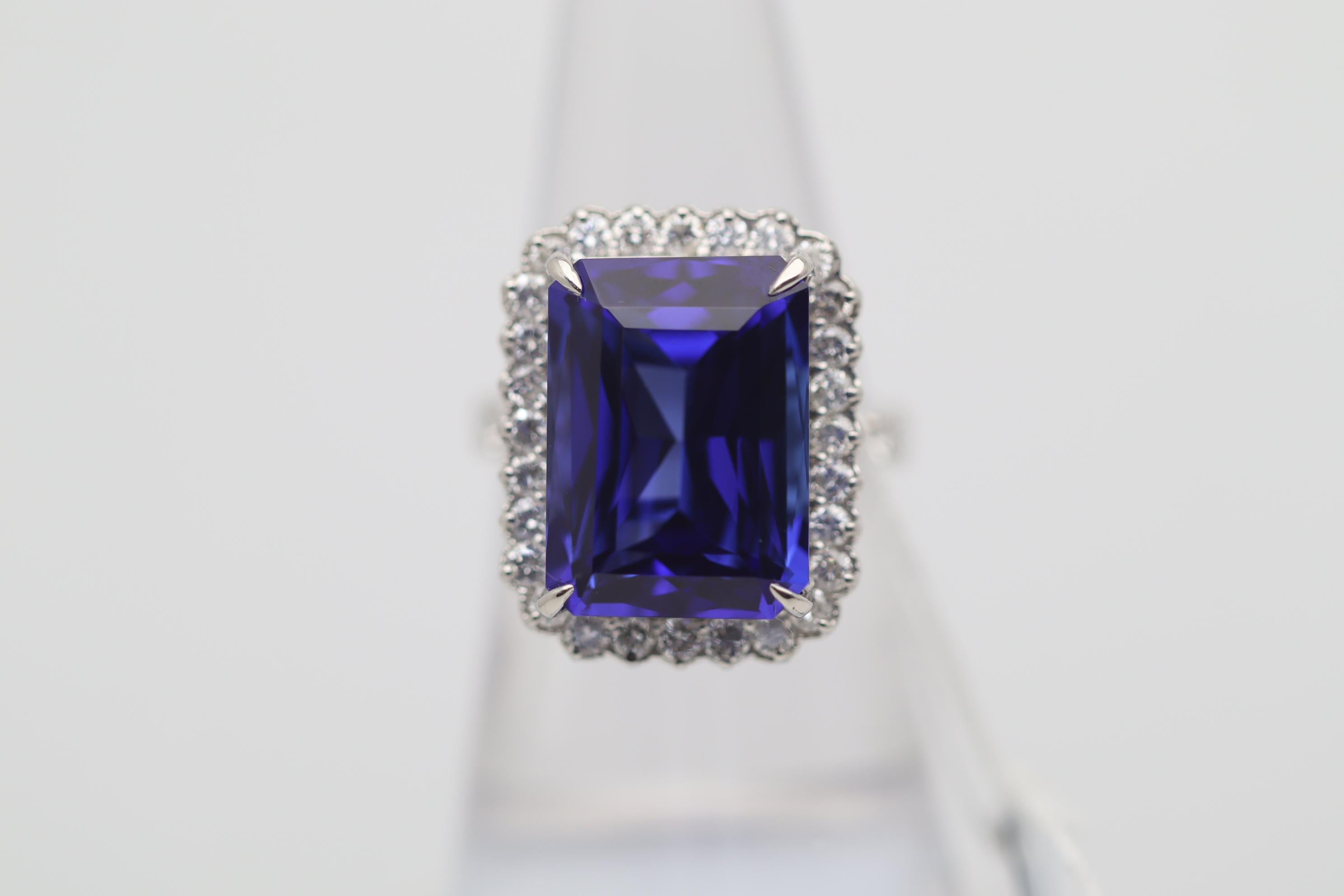 A large, fine, and impressive tanzanite weighing 14.07 carats takes center stage of this platinum made ring. It has a rich highly saturated purple-blue color and a lovely rectangular shape with fine faceting. It is complemented by 0.97 carats of