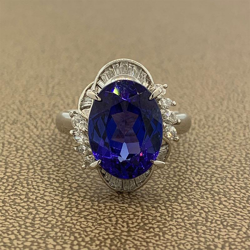 A vibrant ring featuring a 10.57 carat tanzanite. The full of life and gleaming oval gemstone is haloed by 0.80 carats of diamonds. Baguette cut diamonds are channel set above and below the tanzanite with marquise cut diamonds prong set on the two