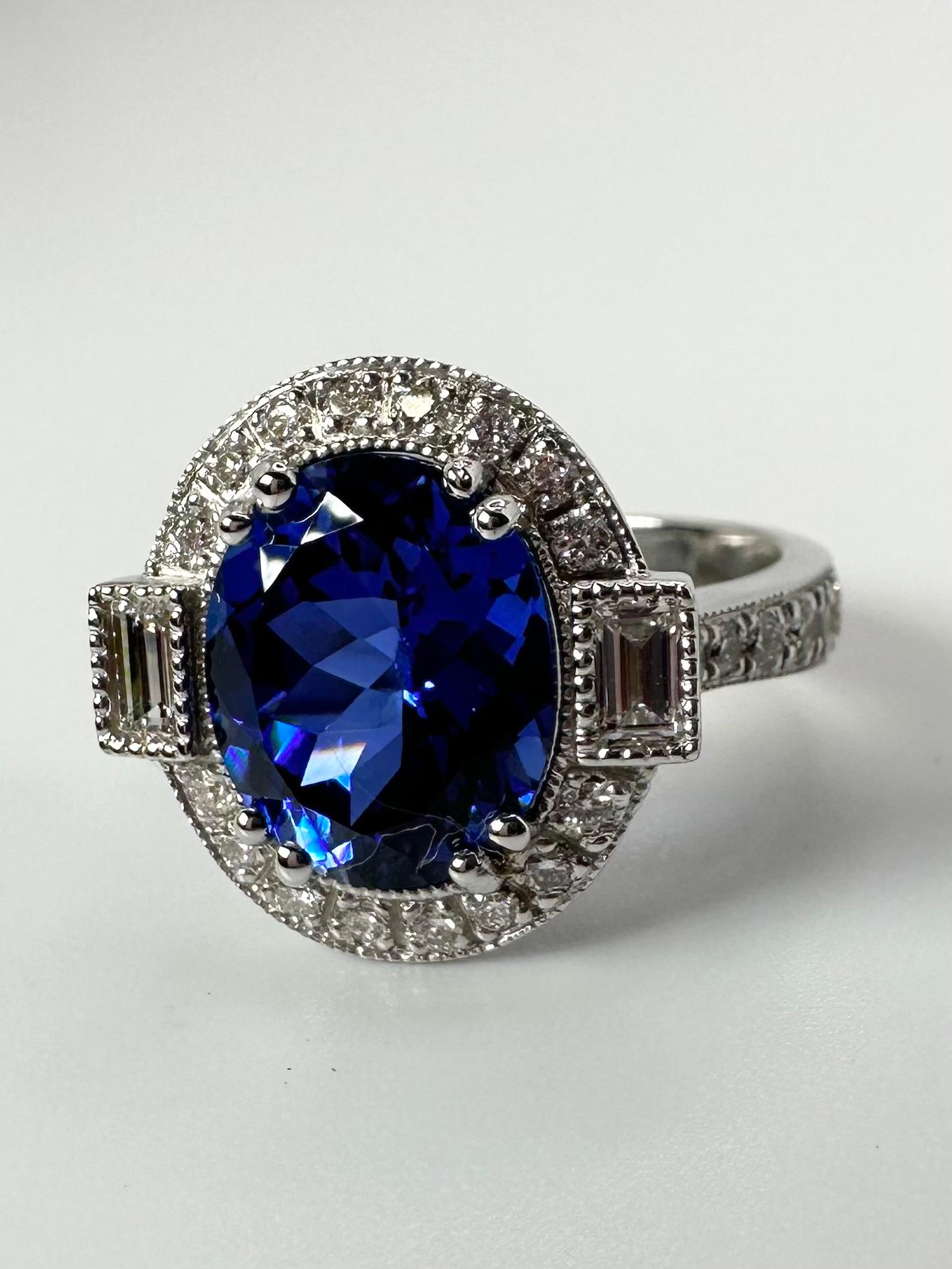Important Tanzanite ring flanked by a diamond on either side, made with a gentle halo in platinum. Stunning rare color!

GRAM WEIGHT: 9.30gr
GOLD: 14KT white gold
NATURAL TANZANITE(S)
Clarity/Color: Slightly Included/Deep Violet
Carat:6.30ct
NATURAL