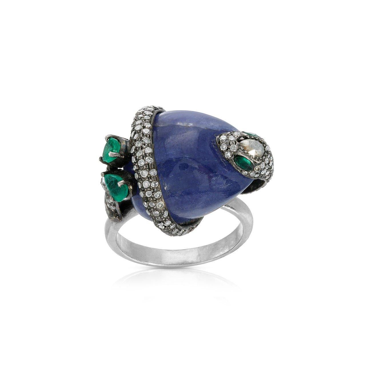 A glittering Diamond snake with fiery Emerald eyes and a Gold-tipped tail coiled around a natural Cabochon Tanzanite and mounted on a modern Silver band with a stylish 18 karat white gold polish.

- Natural Tanzanite weight approx 34.44 Carats.
-