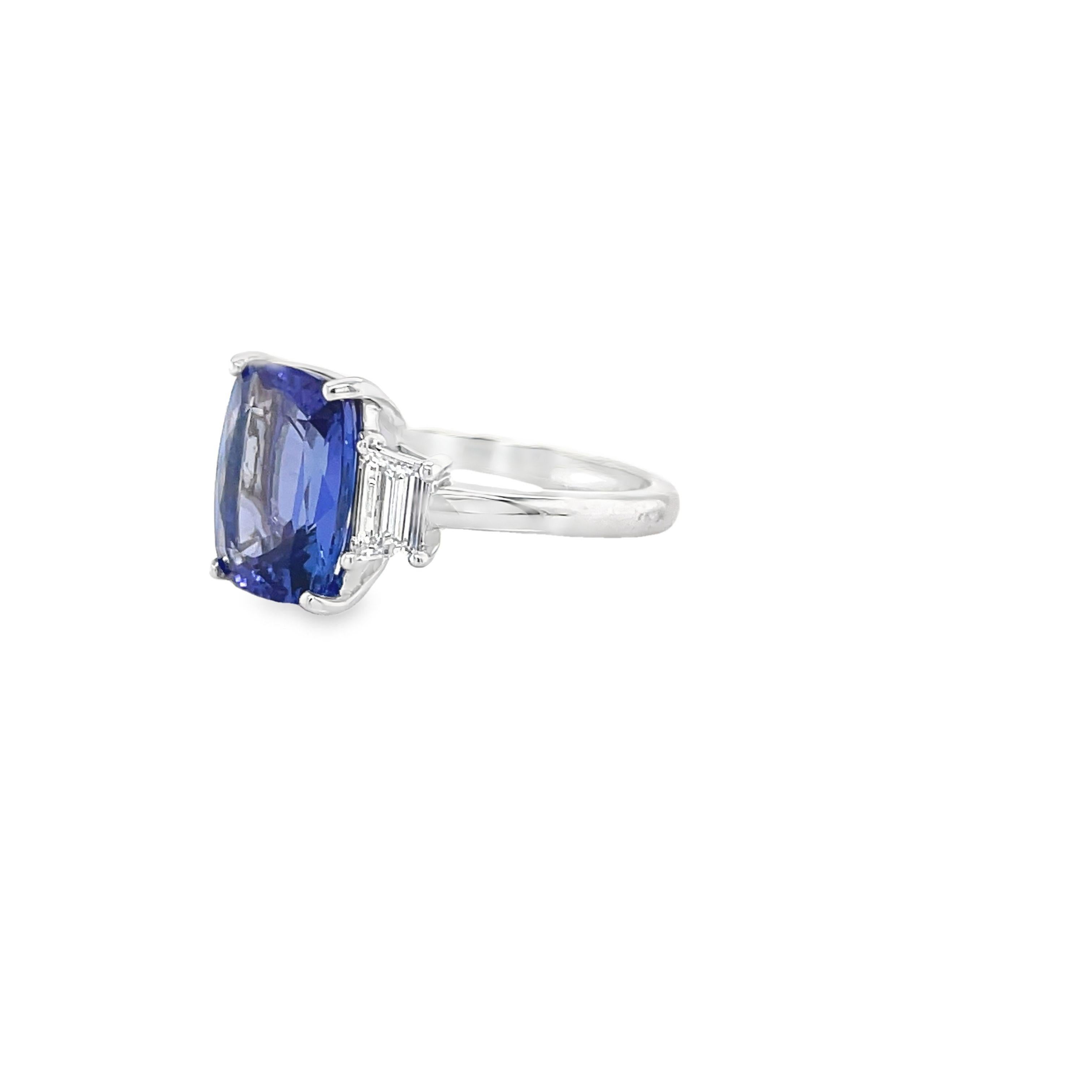 Ring contains one center elongated cushion cut tanzanite, 4.28ct and two matched side stone step cut trapezoids, 0.43tcw. Diamonds are F in color and VS2 in clarity. All stones are mounted in handmade basket prong settings and a 2mm solid shank.