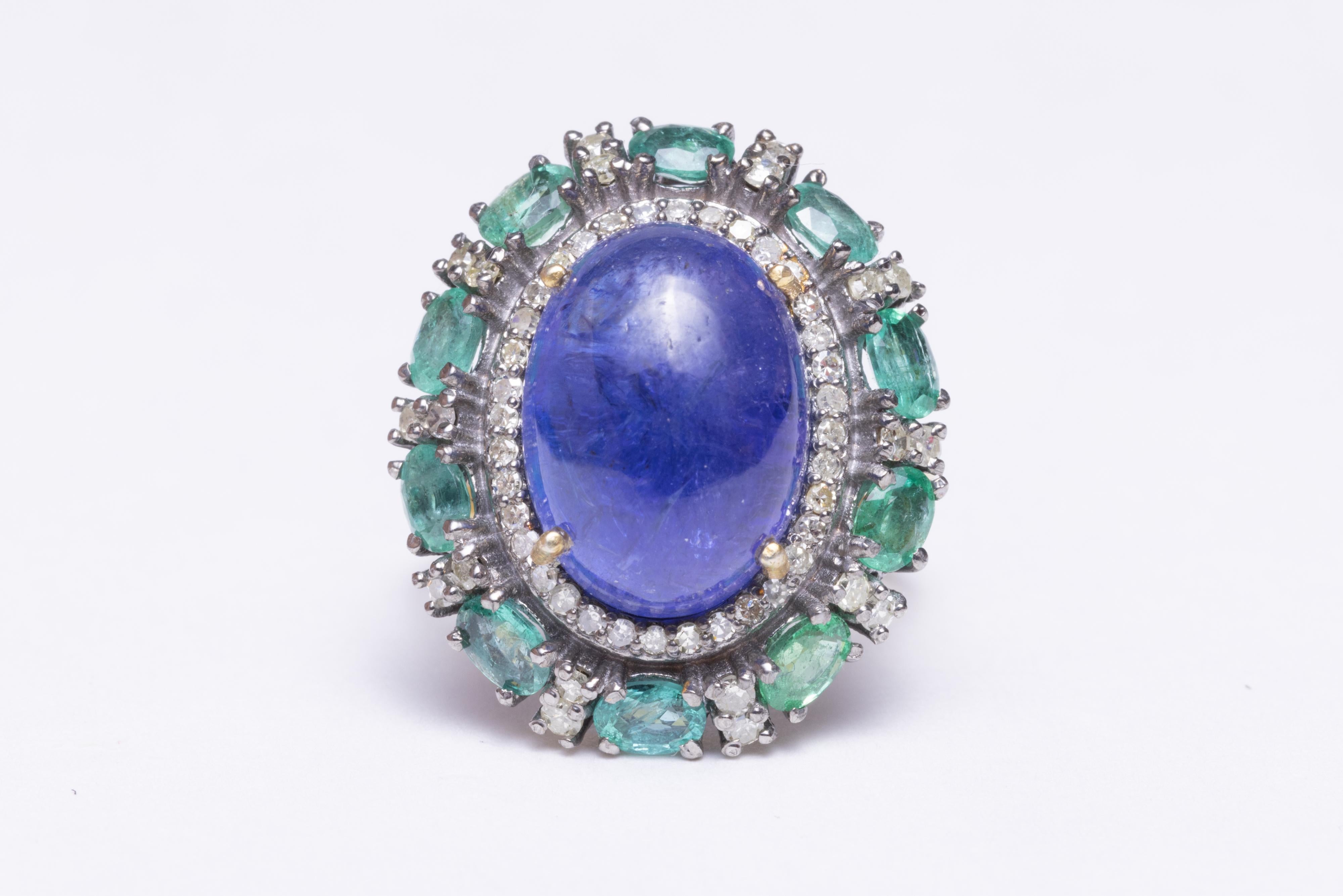 Large cabochon domed Tanzanite center stone surrounded by oval-shaped faceted emeralds and round, brilliant cut diamonds, set in sterling silver with a vermeil band.  Ring size is 6.5
