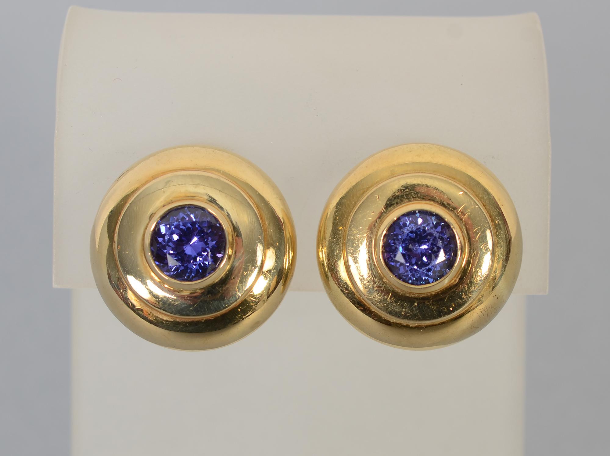 Lovely two tiered round gold earrings centered with a faceted tanzanite. The color of the stones is a rich purplish blue. Clip backs can be converted to posts.