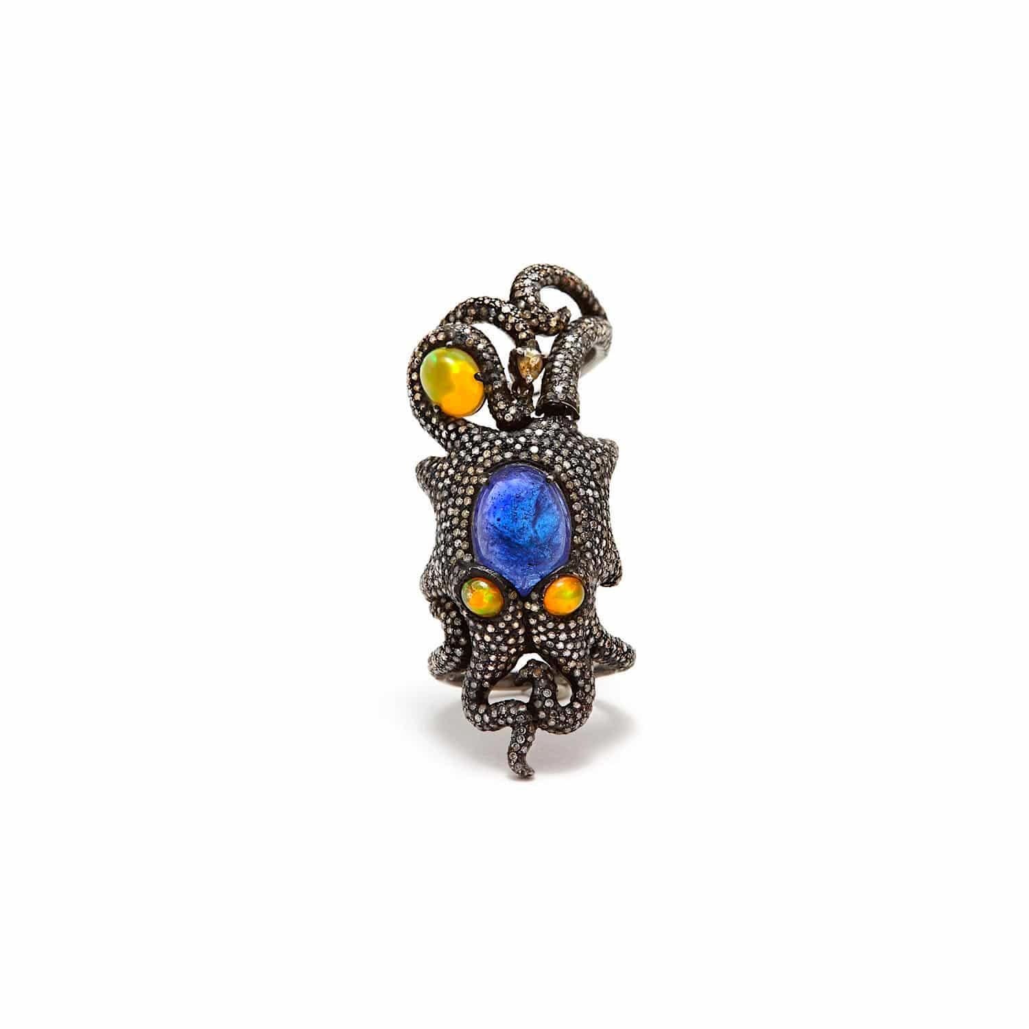 A truly unique piece with a humorous edge... A Diamond set hinged shield ring in a whimsical octopus design featuring a large center cabochon Tanzanite and beady fire Opal eyes staring at you with a larger Opal hugged by a tentacle at the tip... The