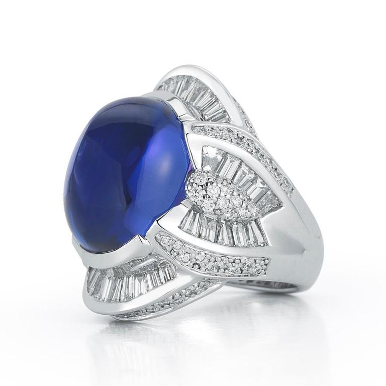 TANZANITE OVAL CABOCHON RING A significant white gold setting featuring diamond baguette accents forms the striking backdrop to this luscious Tanzanite cabochon. Item: # 01667 Metal: 18k W Color Weight: 22.21 ct. Diamond Weight: 3.75 ct.
