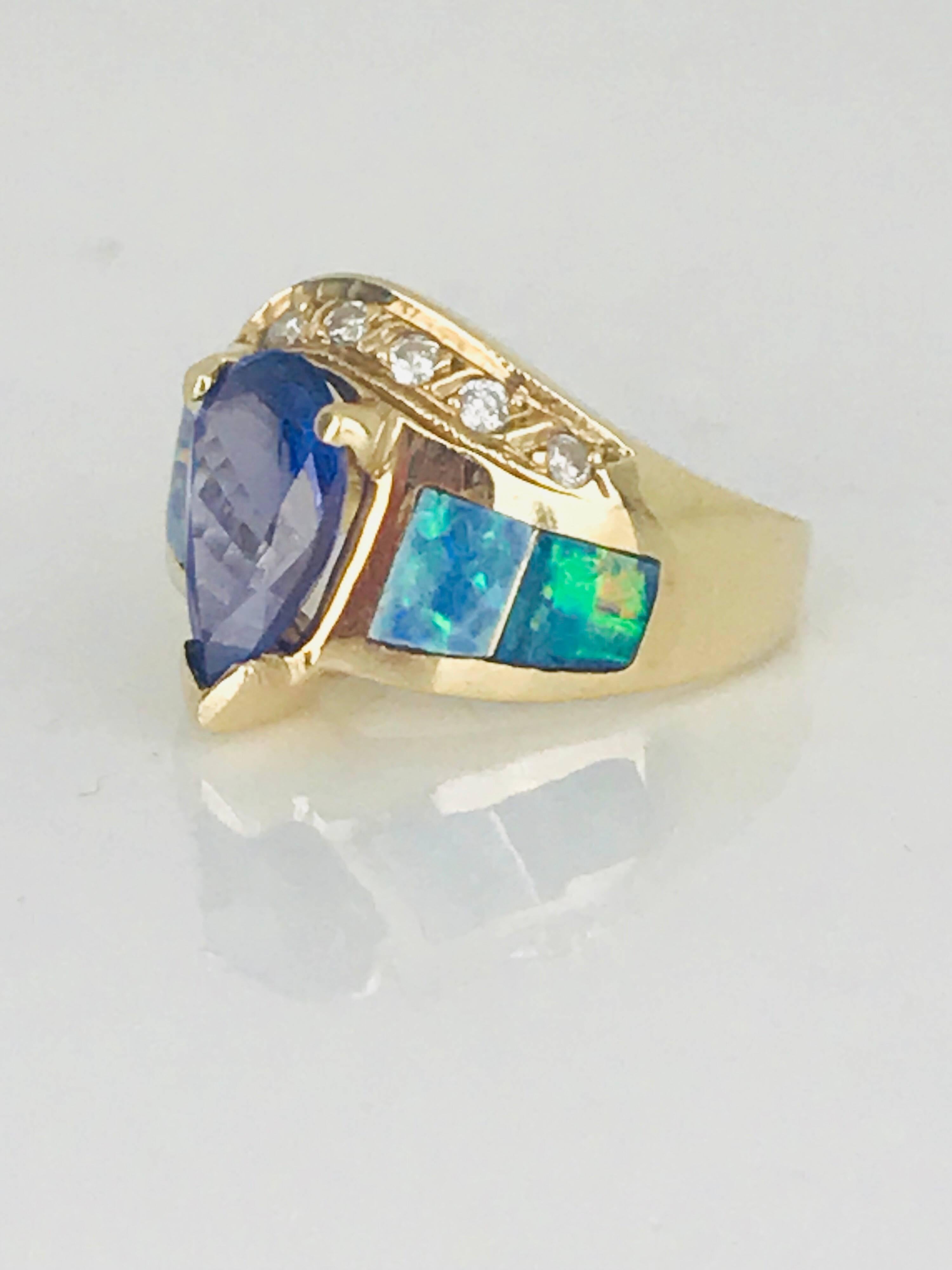 Timeless, 14 karat yellow gold ring with pear-shaped Tanzanite center stone accented with Austrialian opals. The Tanzanite measures 11.43 x 6.47 x 3.00 millimeters in diameter.  The estimated weight of the center stone is 1.40 carat.
Accenting ring