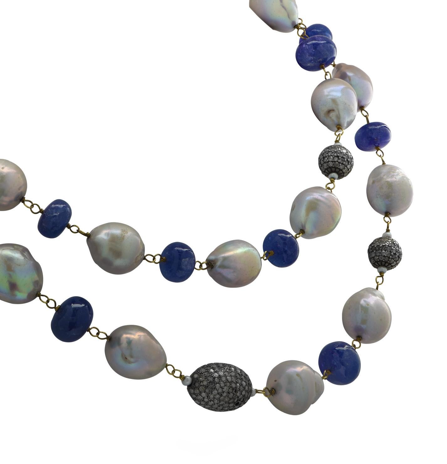 Stunning opera length necklace crafted in 18 karat yellow gold and silver featuring 18 Tanzanite beads weighing 192.8 Carats total, measuring between 9.8 mm and 14.5 mm each, 23 baroque pearls measuring between 13.3 mm and 14.5 mm each and 6 mixed