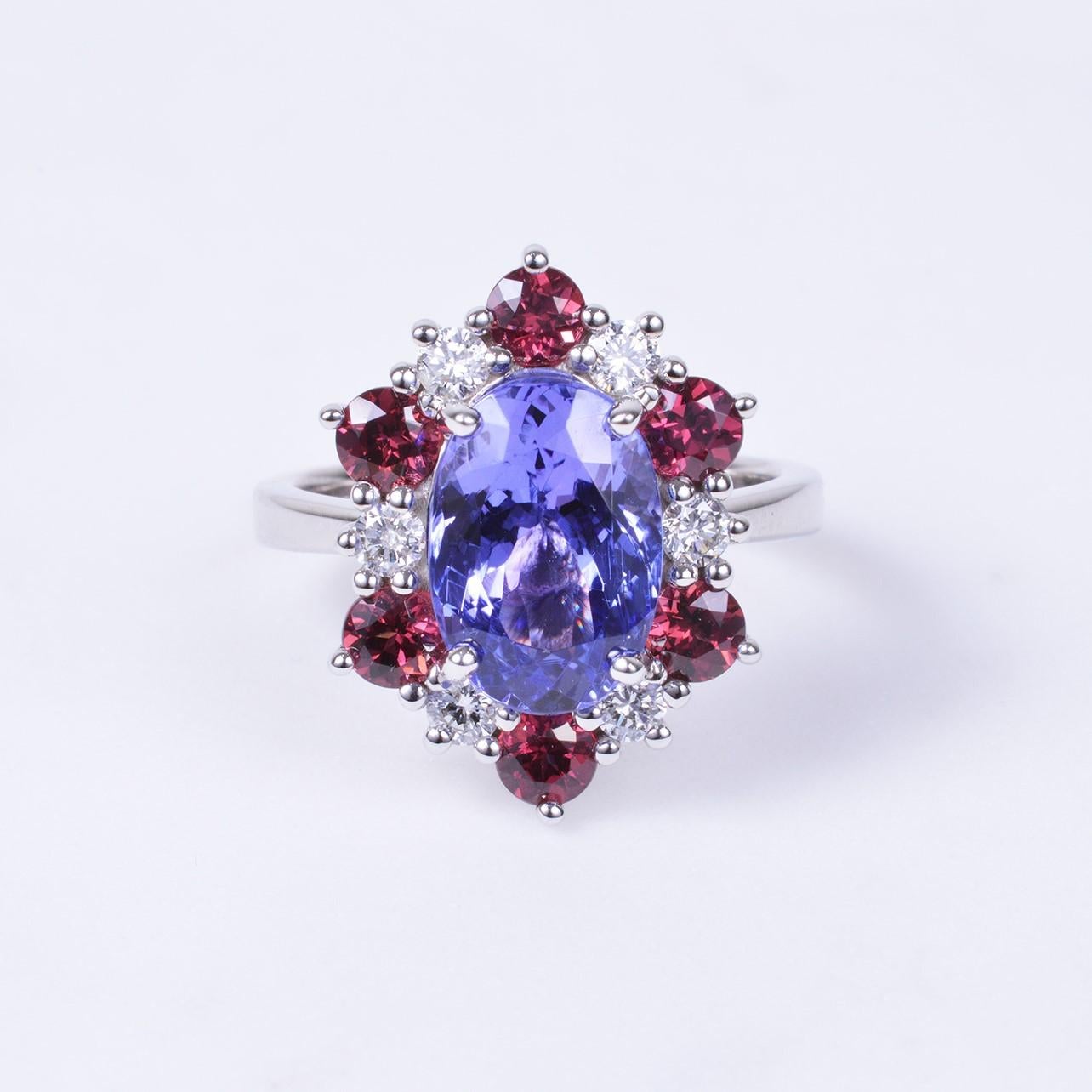 This ring truly is remarkable!! With a gorgeous 3.90 carat oval cut tanzanite in the center surrounded by 1.38 carats of rhodolite garnet and .32 carats of diamonds. All hand set in 14k white gold. Ring size is 6.25.