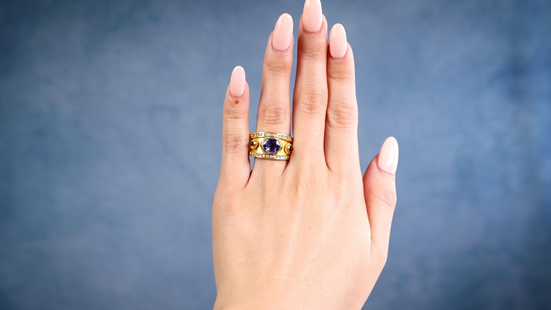 Ein Tansanit Rubin Diamant 22k Gelbgold Ring. Mit einem ovalen Tansanit im Brillantschliff mit einem Gewicht von etwa 1,20 Karat. Akzentuiert durch zwei Rubine im Cabochon-Schliff mit einem Gesamtgewicht von ca. 0,15 Karat und 26 runde Diamanten im