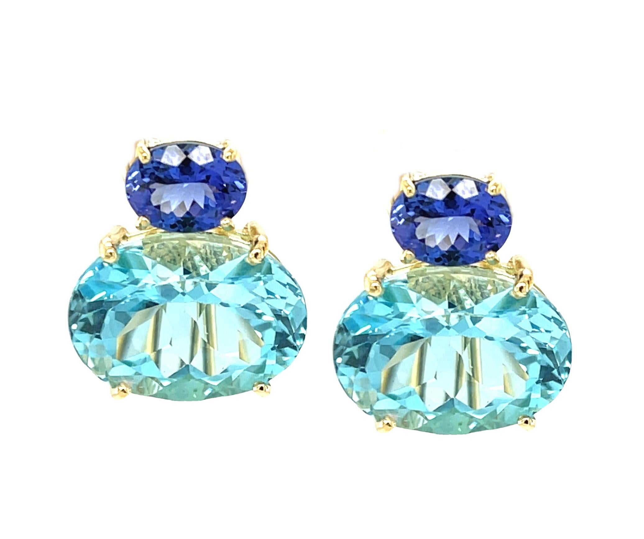 These impressive earrings feature a beautifully matched pair of Swiss blue topazes that have a combined weight of over 23 carats! The large sparkling ovals are set horizontally with gorgeous African tanzanites in an original color block design that