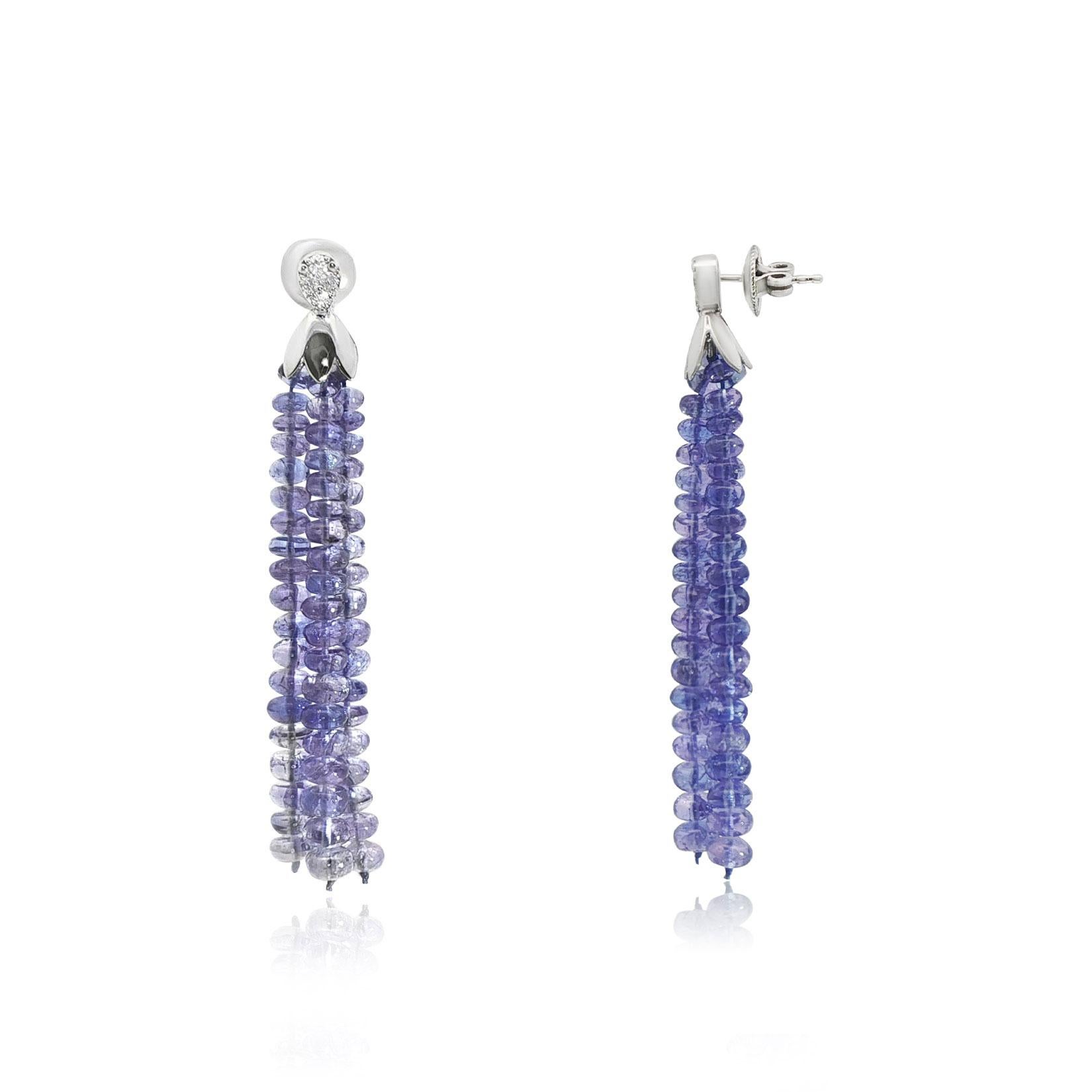 Questi squisiti orecchini sono caratterizzati da perle di tanzanite rotonde disposte in eleganti nappe, che irradiano una ricca tonalità blu-viola che cattura la luce a ogni movimento. Ogni nappina è sormontata da un cappuccio in oro bianco 14k