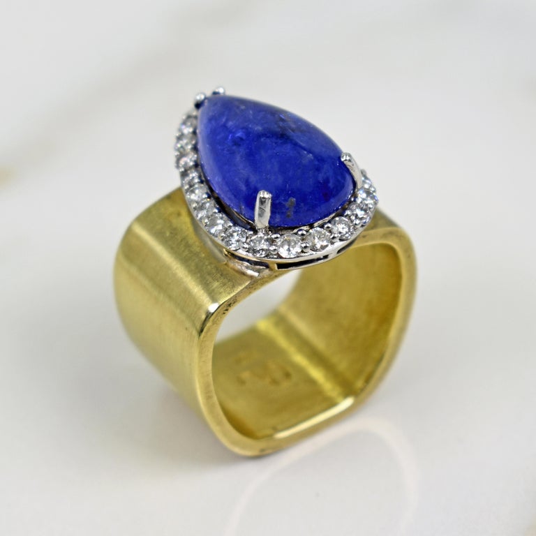 Gorgeous, purplish-blue Tanzanite teardrop / pear shaped cabochon gemstone and Diamond halo set in 14k white gold on a brushed, square 14k yellow gold cocktail ring. Size 7. Beautiful colored gemstone in a timeless and chic setting with a