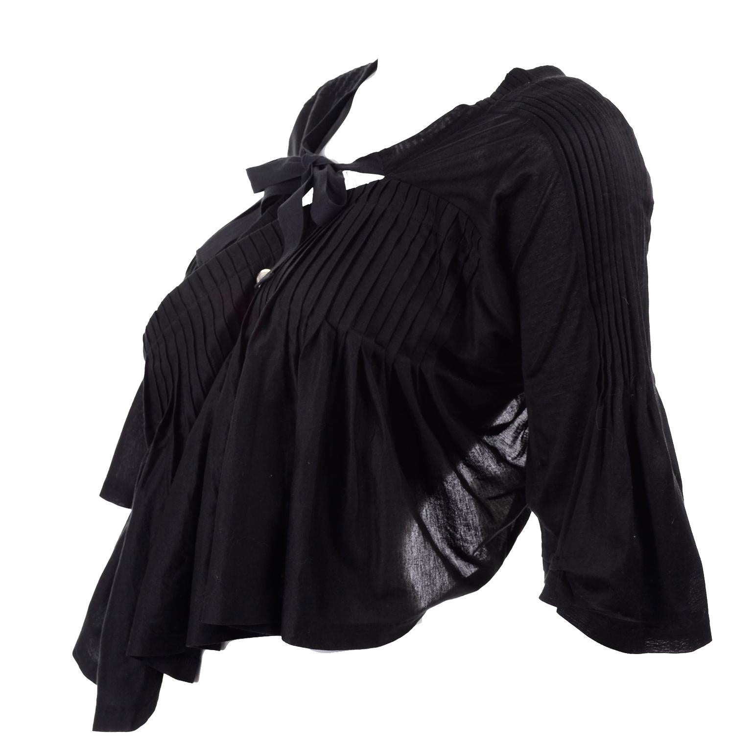 This is a fabulous top from Comme des Garcons with the original $1065 price tag and all other tags still attached . Purchased at Barney's, this avant garde top has an open back, beautiful pleats & tucks, and is in a poncho style with 3/4 length