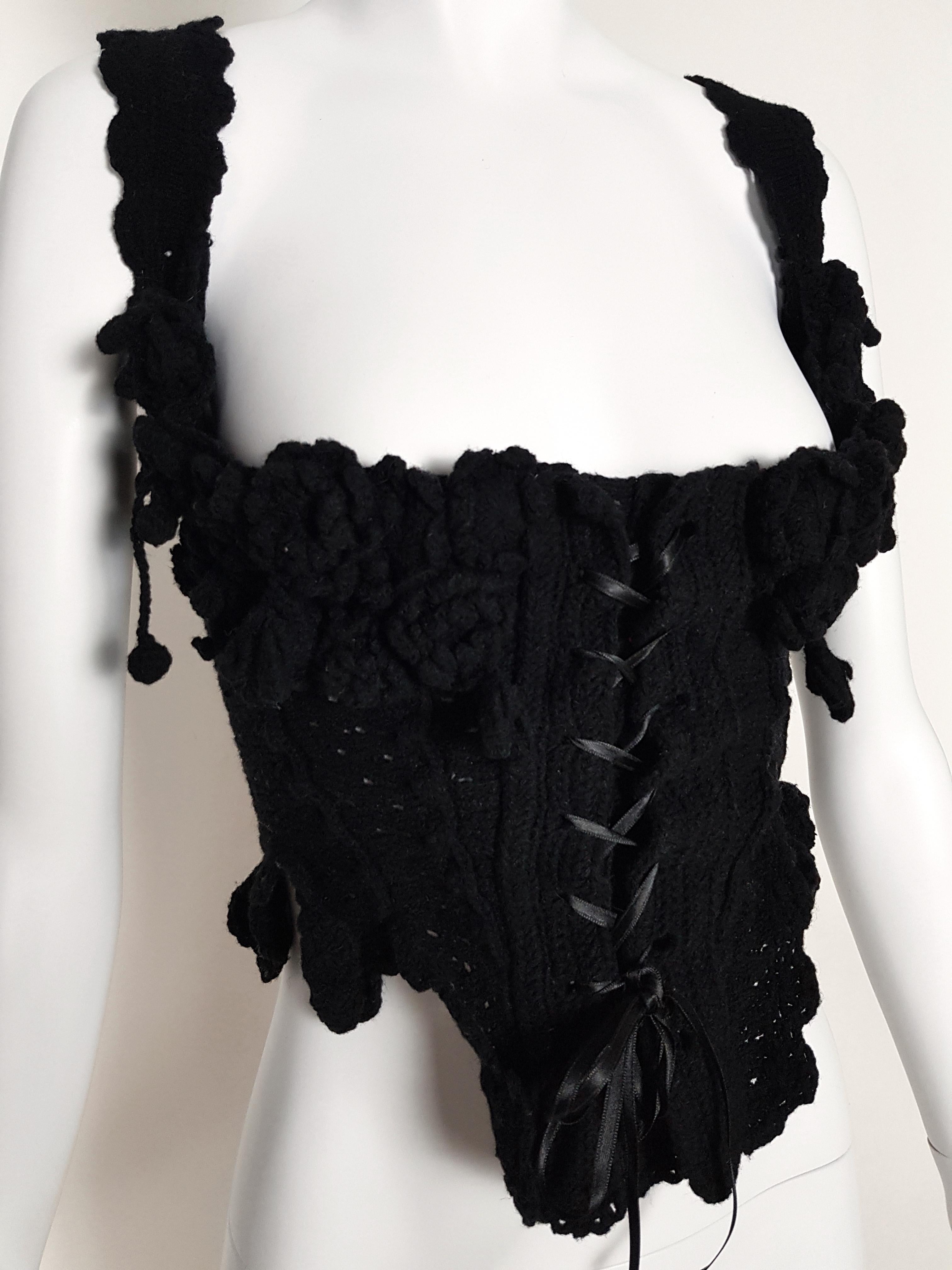 A rare piece with endless hand knitted flowers and details.
- Unstructured asymmetric pattern
- Black ribbons front fastening 
- Knitted straps adjustable on the back with black ribbons
- Marked Size S (but front corsage adjustable with ribbons)
-