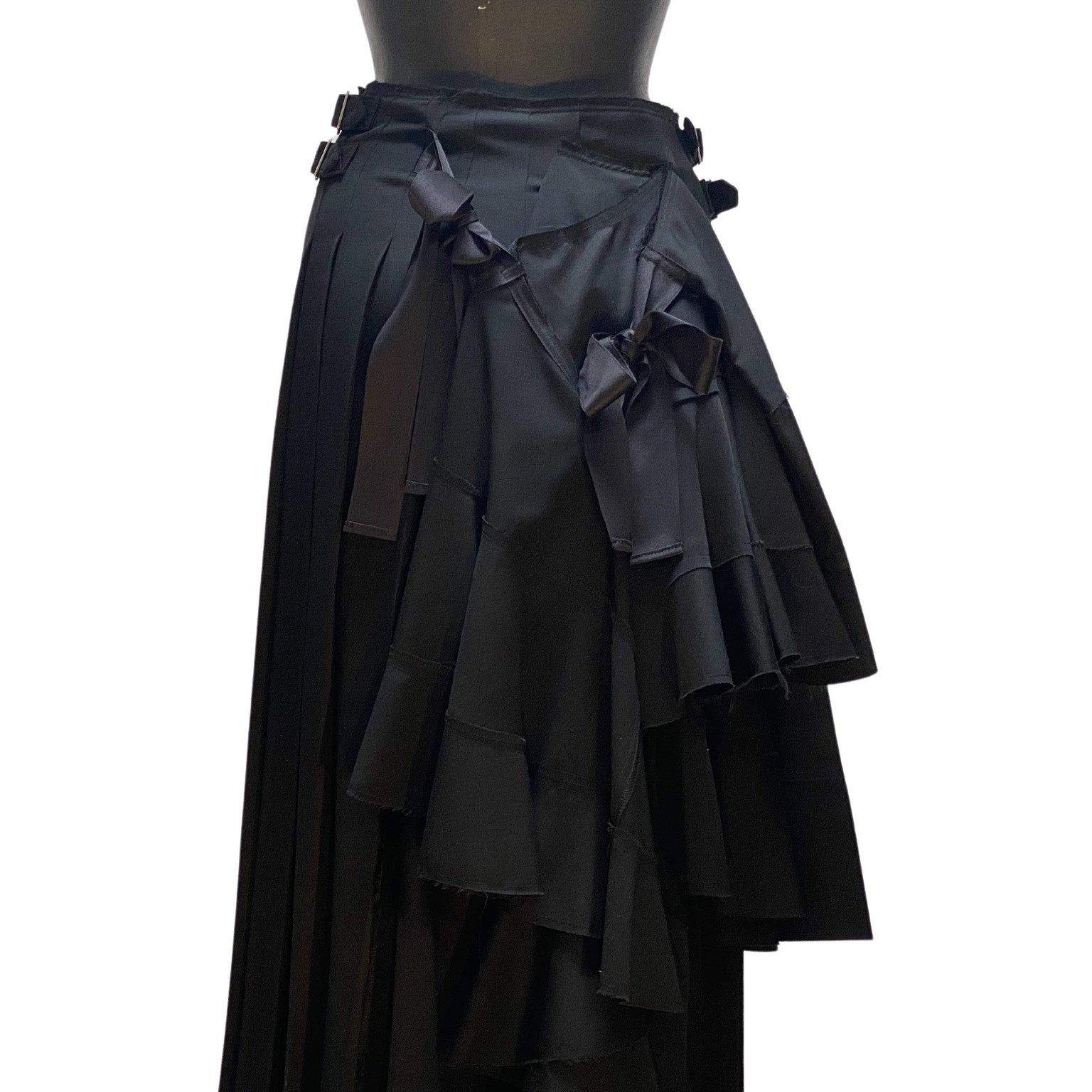 This luxuriously weighty, black pleated wool skirt wraps around and secures with two sturdy attached self-fabric buckles at each hip. The captivating back view features magnificently flowing layers, not to be outdone by the two elegant satin bows. A
