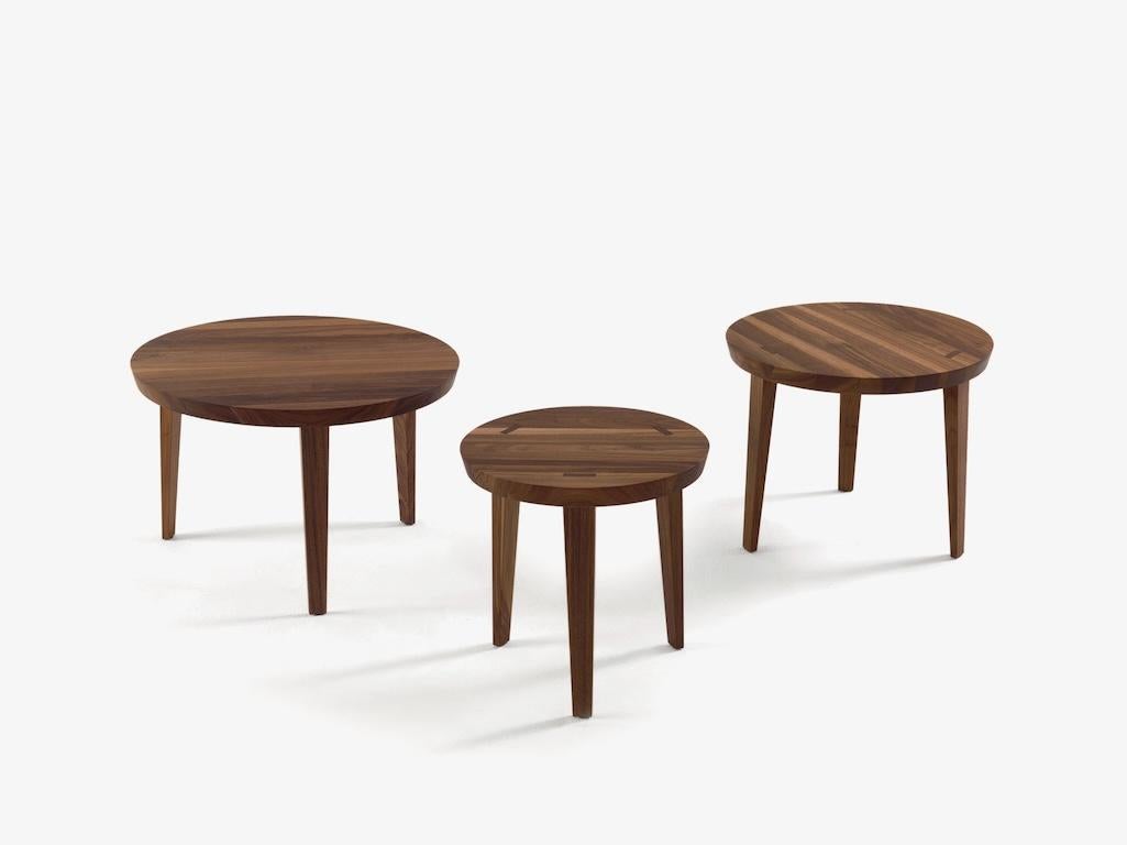 Serie von kleinen Tischen aus Massivholz, erhältlich in verschiedenen Durchmessern und Höhen, mit der Möglichkeit, sie übereinander zu stapeln. Die Beine gehen durch die Oberseite hindurch und sind an der Oberfläche sichtbar.

Hergestellt in