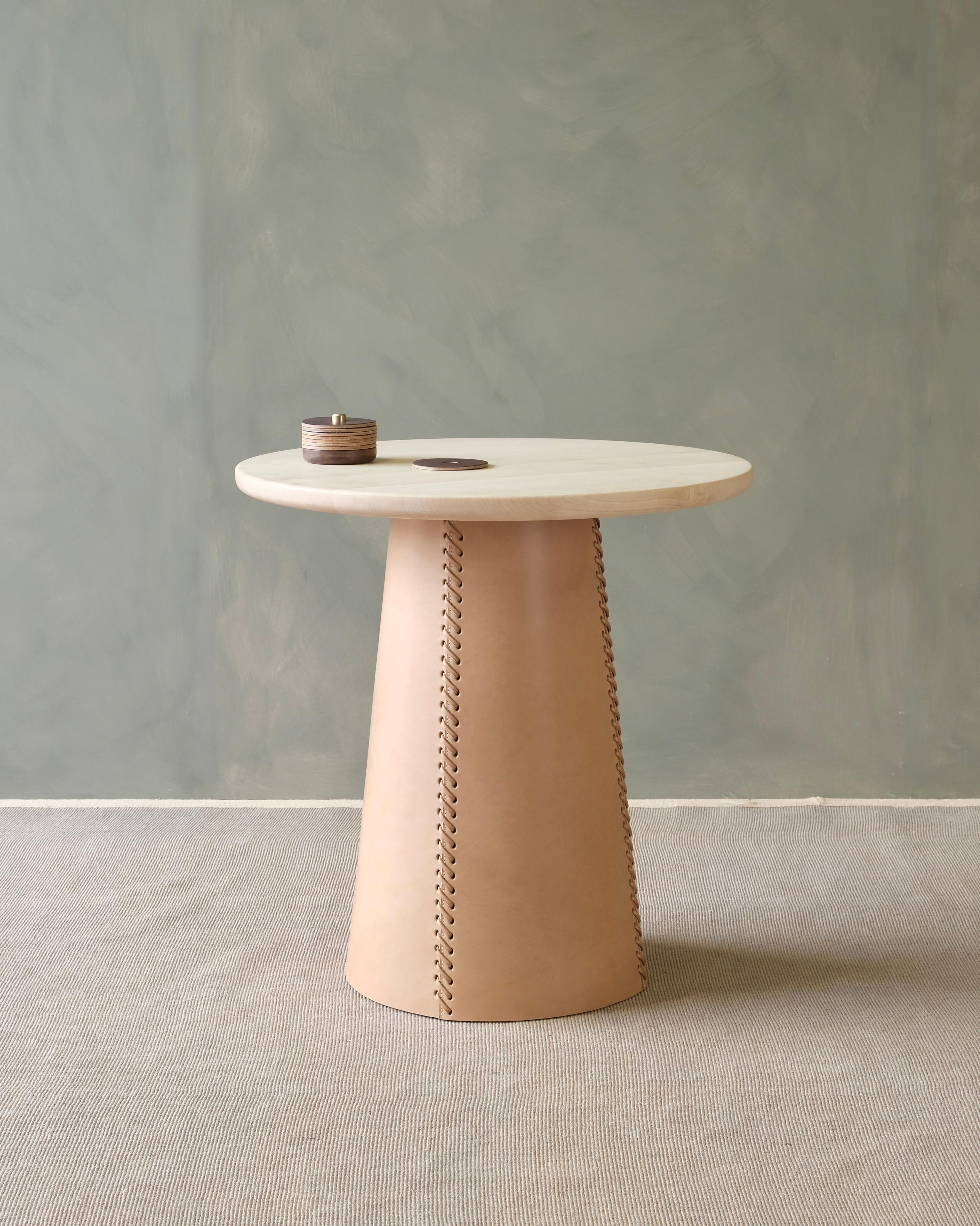 The Taper side table fuses traditional leather corking techniques with contemporary organic modern style. Each hand turned from solid wood on a lathe before being fitted with an oak bark tanned bridle leather sleeve. The leather is hand cut and
