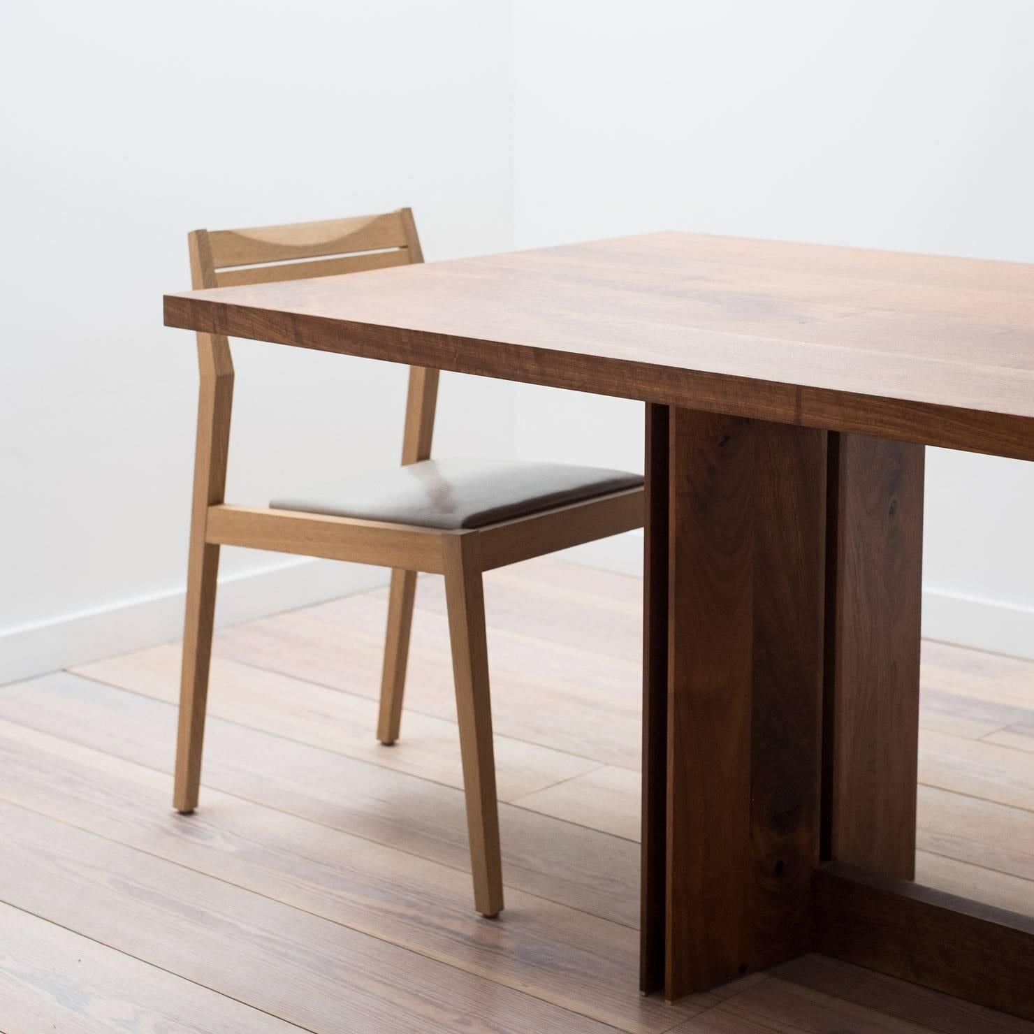 The Tapered Dining Table, made from solid black walnut, showcases the quality and beauty of each hand-selected board of wood. The base of this table pairs strikingly thin edges with negative space, creating a strong, yet light appearance. This piece