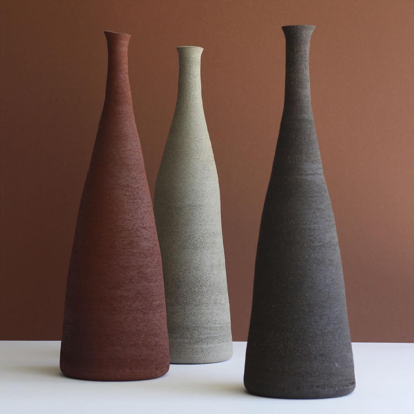 Harmonische Linien bestimmen die elegante Silhouette dieser flaschenartigen, dekorativen Vase aus Steinzeug, einem geduldig von Hand gefertigten Einzelstück, das wirklich einzigartig ist. Eine zerkratzte Textur verbindet sich tadellos mit dem