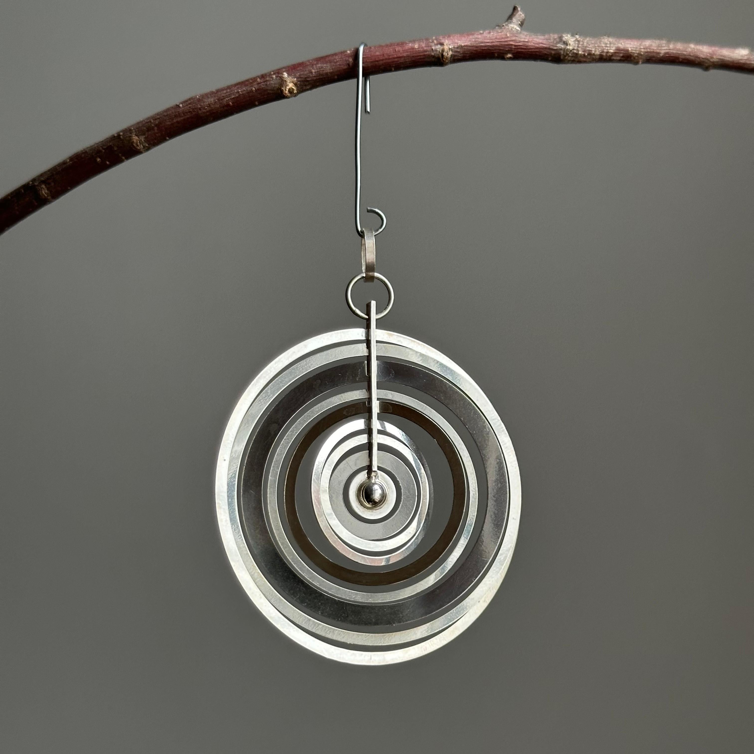 Hopeakuu (finnisch: Silbermond) Sterling-Anhänger, entworfen von Tapio Wirkkala. Er besteht aus neun konzentrischen Ringen, die sich unabhängig voneinander um eine kleine Kugel am Ende einer vertikalen Halterung bewegen und so ein tragbares