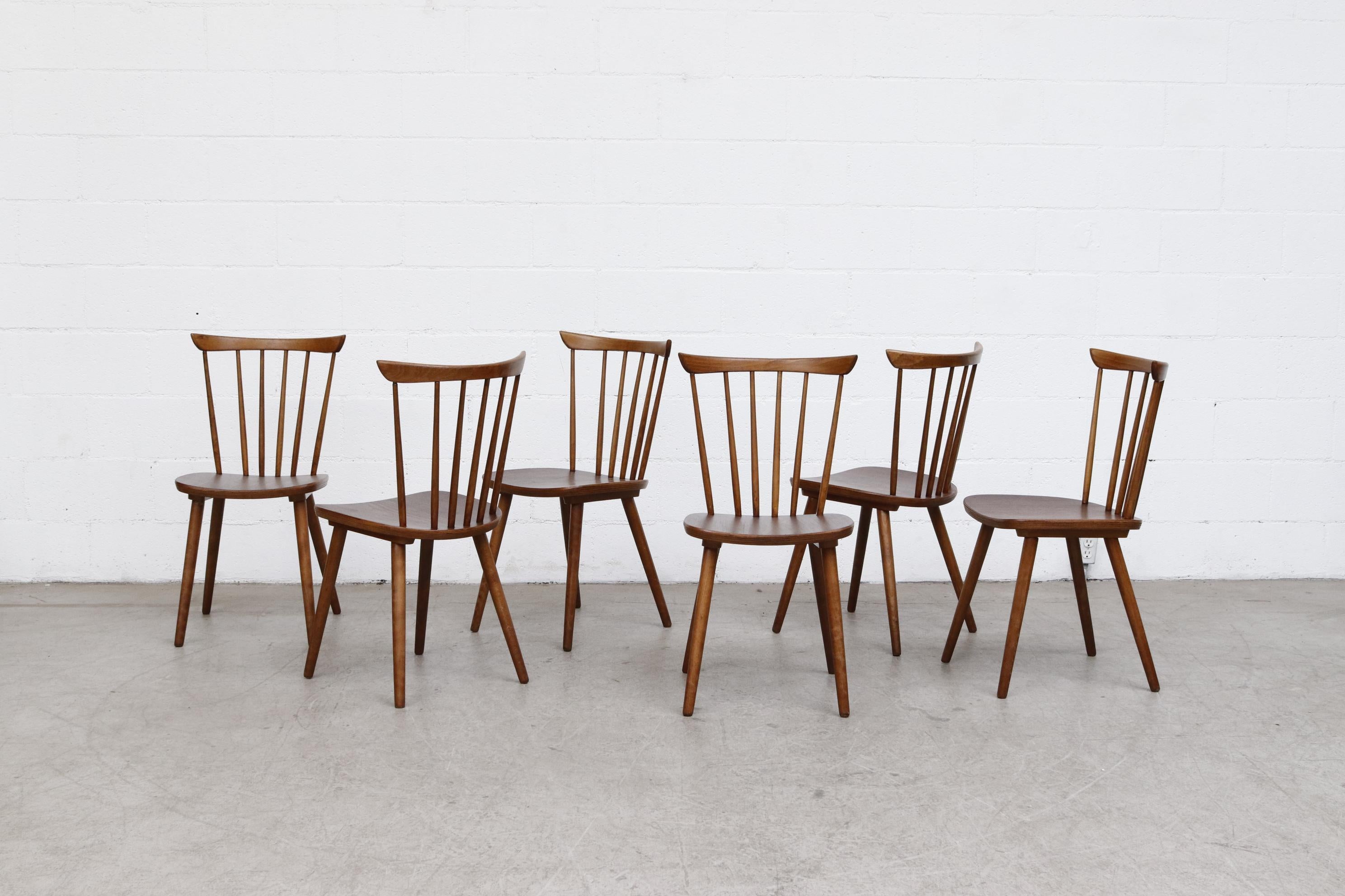 Midcentury Tapiovaara style spindle back dining chairs with clean lines with bowed back rest. In good overall condition with wear consistent with their age and usage. Individually listed.