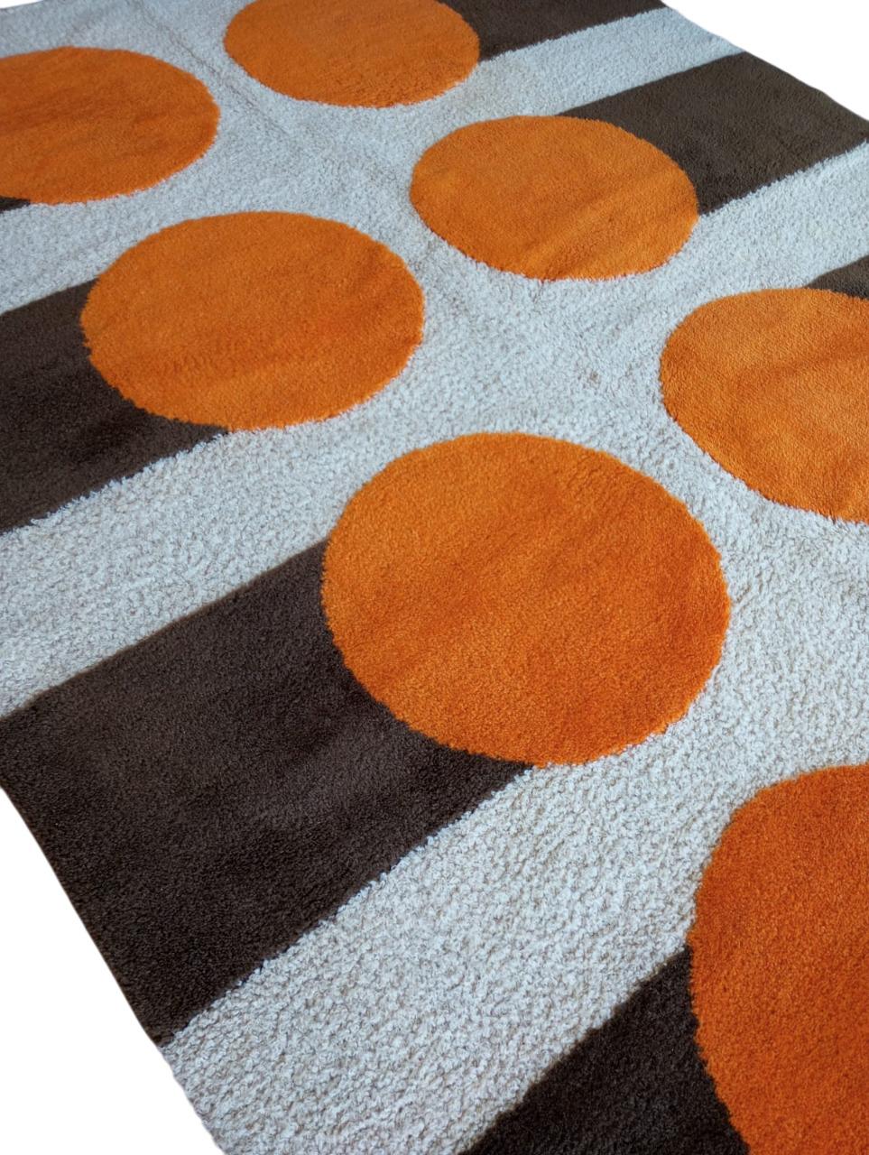  Il tappeto con design geometrico retrò molto distintivo anni ’70. Attribuito a Verner Panton (1926 -1998) designer Danese.
In lana con dimensioni 270 cm. x 192 cm. La base è di colore beige chiaro, con sei grandi cerchi arancioni disposti in due