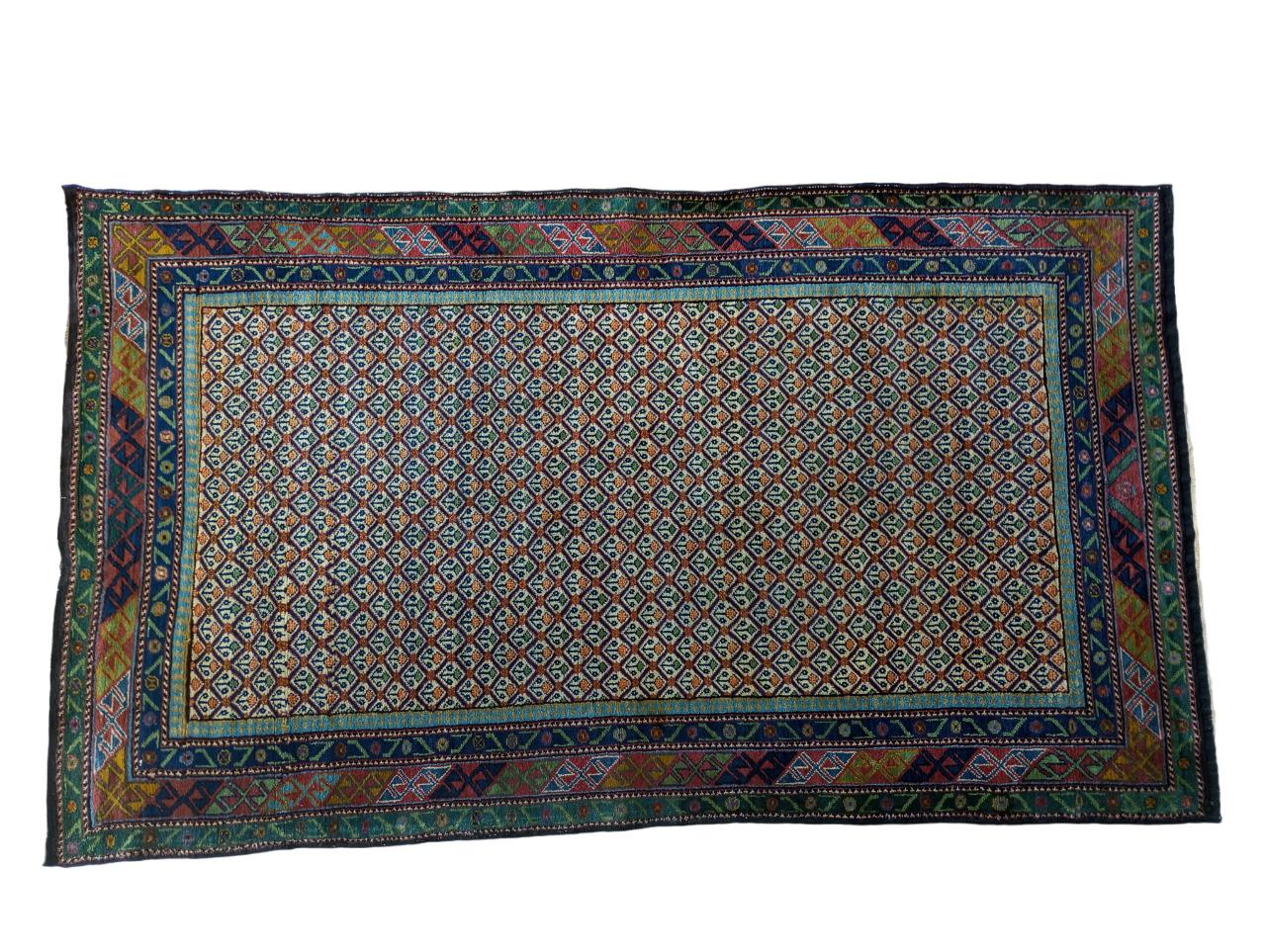 Tapis indien noué à la main en pure laine avec chaîne et trame en coton mesurant 225 cm. x 128 cm. Année de production 1920/30.
Le dessin central est caractérisé par un motif continu de petits losanges de couleur claire, chacun orné de fleurs