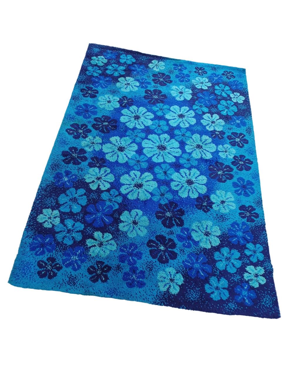Tappeto Danese in pura lana degli anni ’70  con un motivo floreale molto vivace con varie tonalità di blu, dal turchese al blu scuro.
Il disegno presenta fiori stilizzati distribuiti uniformemente su tutta la superficie. L’insieme dà un effetto