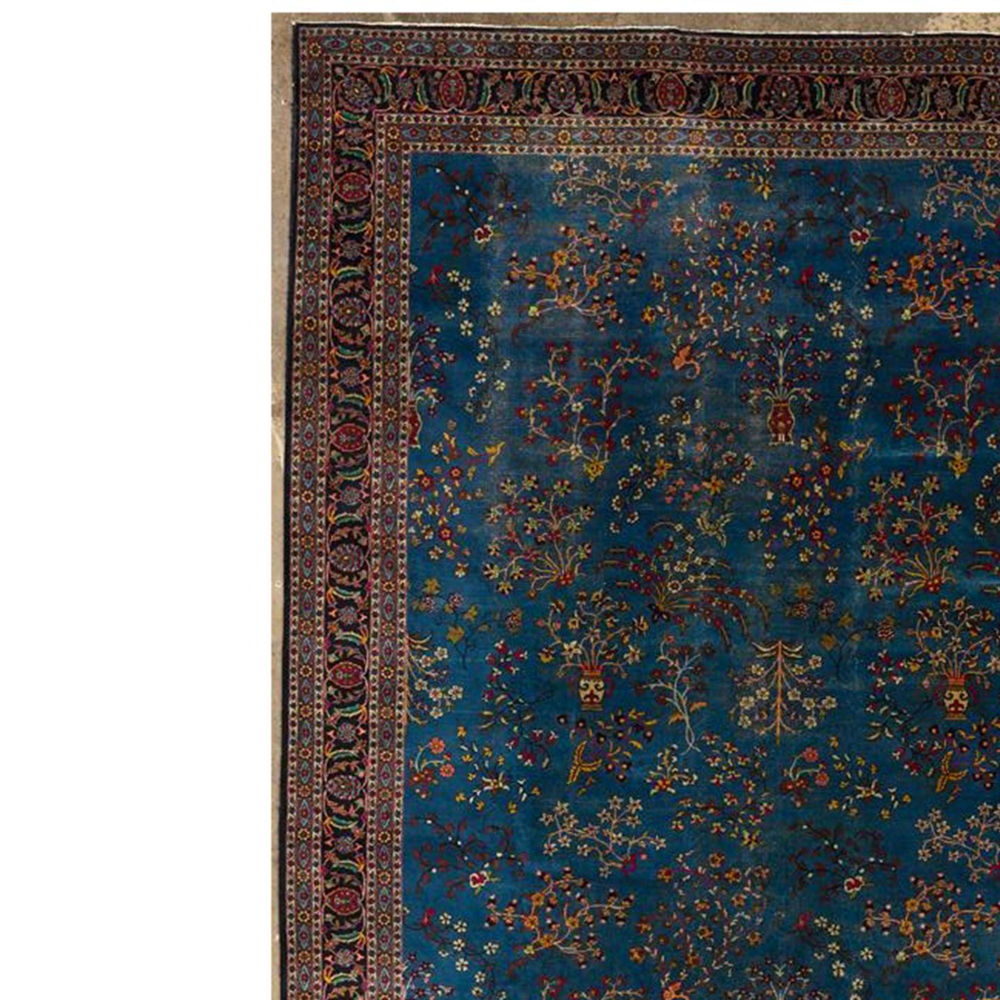 Alfombra de origen persa clásico, en cuya superficie aparecen ornamentos florales sobre fondo oscuro, ribeteados con minuciosos detalles. El tono predominante es el azul oscuro. La alfombra está hecha de lana anudada a mano.