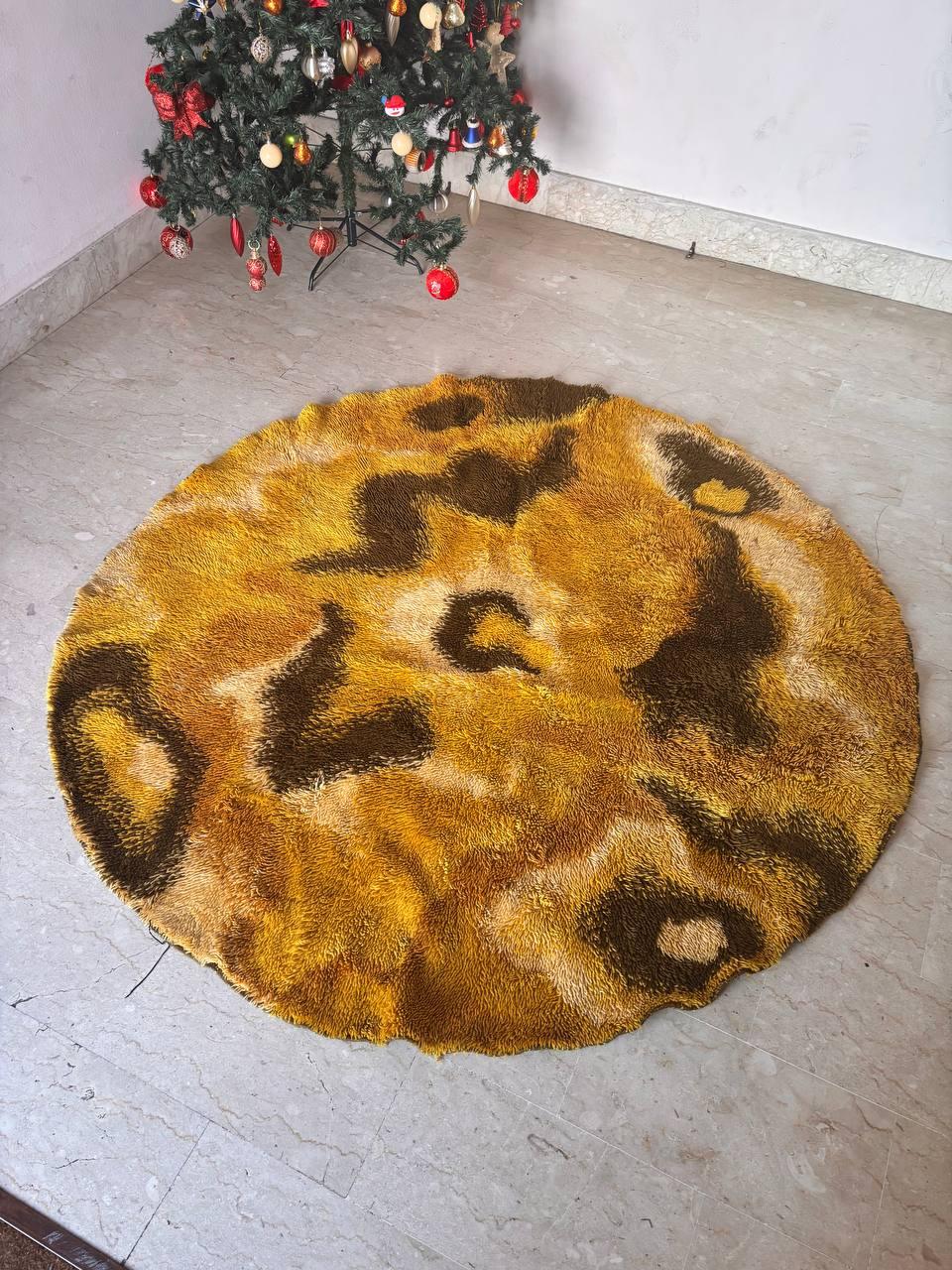 Certainly! Here is a concise description of the carpet:
Vintage circular rug with a bold and modern design. Dominated by warm shades of yellow ochre and brown, it features an abstract pattern with sinuous and irregular shapes that create a dynamic