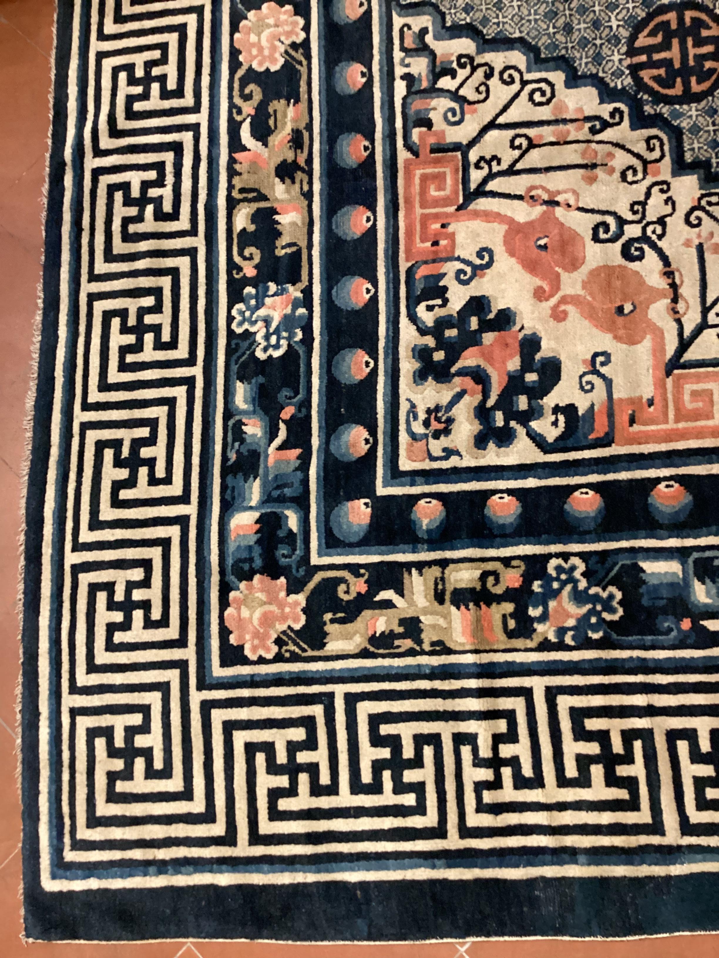 Tapis mongol noué à la main, 100 % laine 19e siècle.
Un grand médaillon s'ouvre sur un champ central avec une petite grille. Au centre se trouve le symbole SCHOU, qui représente la longévité et la chance, entouré de cinq chauves-souris.
 La