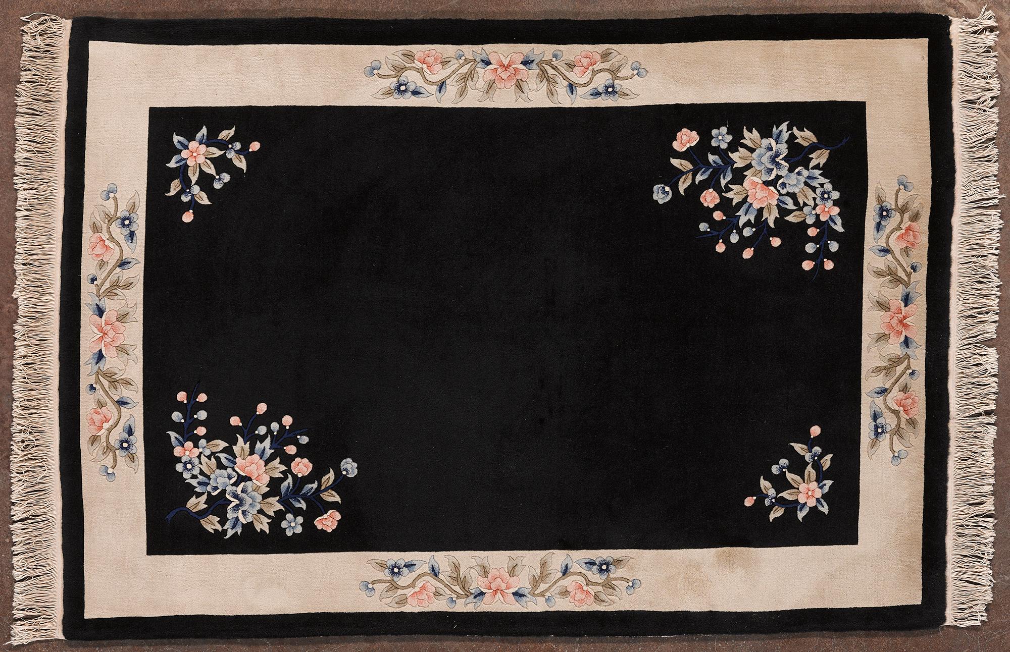 Dieser handgeknüpfte chinesische Teppich hat einen tiefschwarzen Hintergrund, der die raffinierten floralen Motive in Pastelltönen zur Geltung bringt. Die beigefarbene, mit Blumen und geschwungenen Details verzierte Bordüre verleiht einen Hauch von