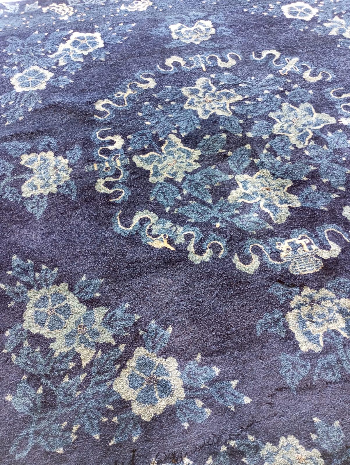 Esta alfombra china de Pekín  principios del siglo XX con el tradicional color azul oscuro, con motivos florales en azul claro y blanco.
 En el centro hay un gran medallón floral con flores estilizadas (las peonías simbolizan la nobleza y la