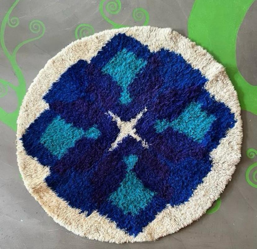 Runder Teppich aus zotteliger Faser mit geometrischem Blumendekor, 1970er Jahre
Runder Teppich  aus weicher, langhaariger, zotteliger Faser. Das zentrale Motiv wird von einer stilisierten geometrischen Blume dominiert, die typisch für die grafische