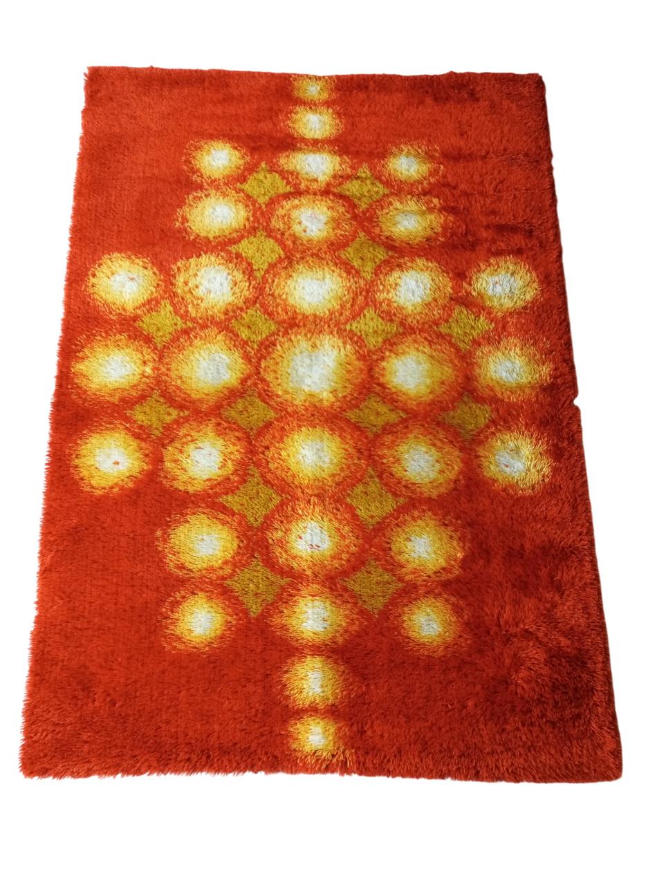 Made by renowned Danish manufacturer Ege Taepper, this rug represents the excellence of Rya patterns, known for their bold, personality-laden patterns. Vibrant shades of deep orange and yellow bring warmth and energy to any room.
In the center, it