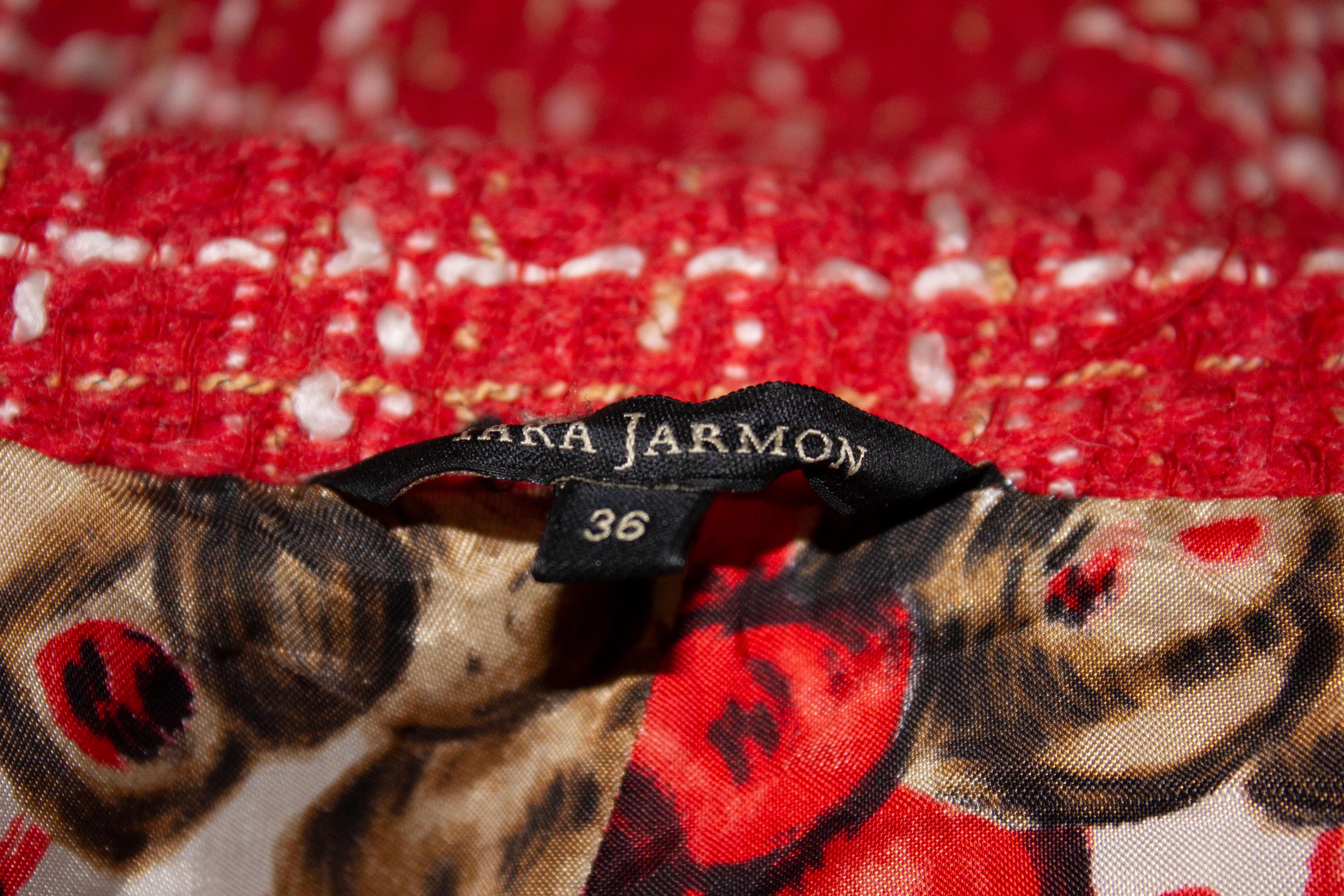 Un manteau amusant de Tara Jamon. Le manteau est en tissu rouge et blanc avec une magnifique doublure. Elle s'ouvre sur le devant par quatre boutons, possède un col rond et une demi ceinture dans le dos. 
Mesures : Poitrine 34/5'', longueur 40''