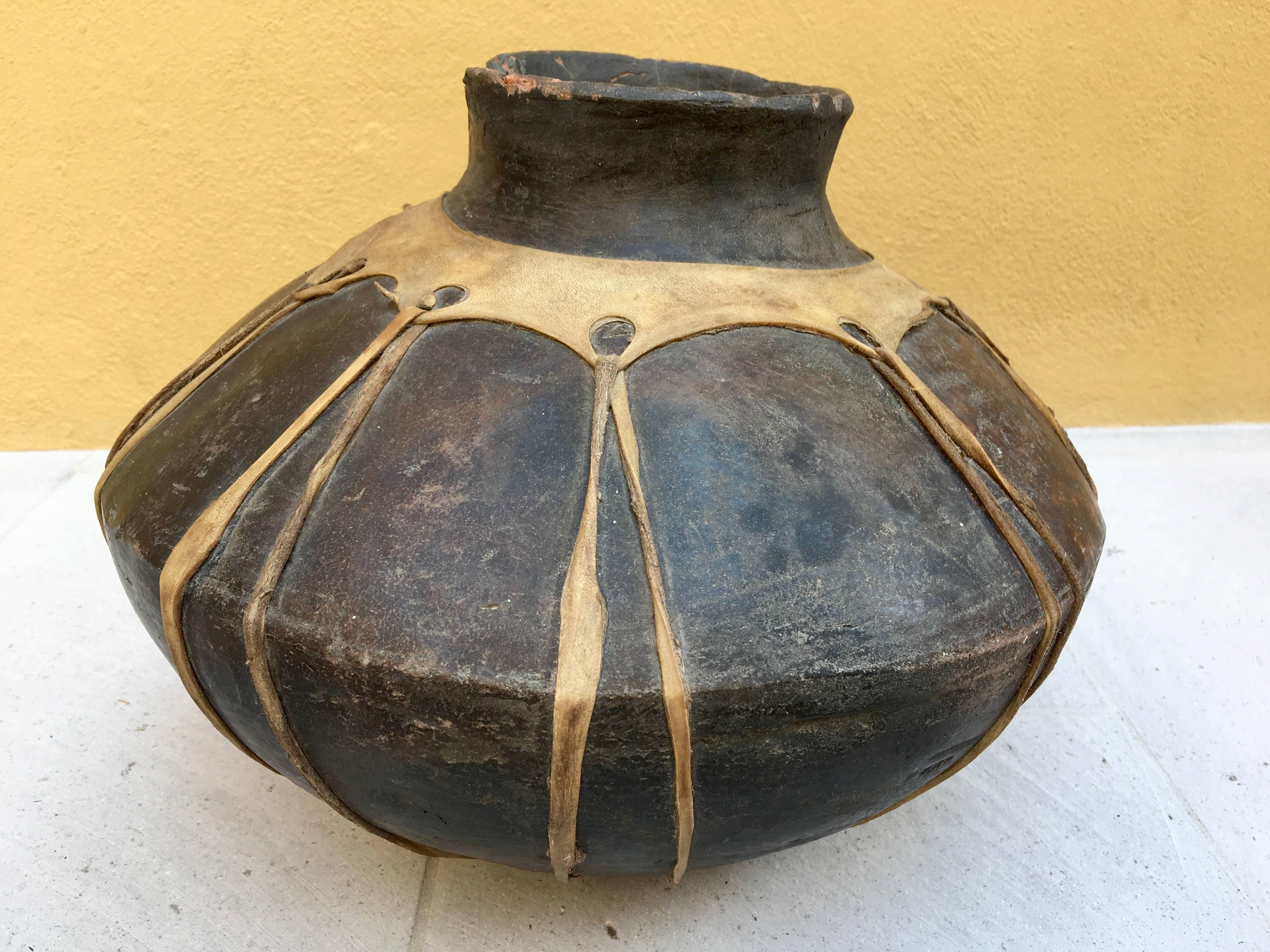 Late 19th century, ceramic water vessel from the Raramuri or Tarahumara people of Chihuahua, Mexico. The pot is traditionally wrapped with pig trip for protection. The vessel represents Fine craftsmanship and skill in pottery that the Tarahumara