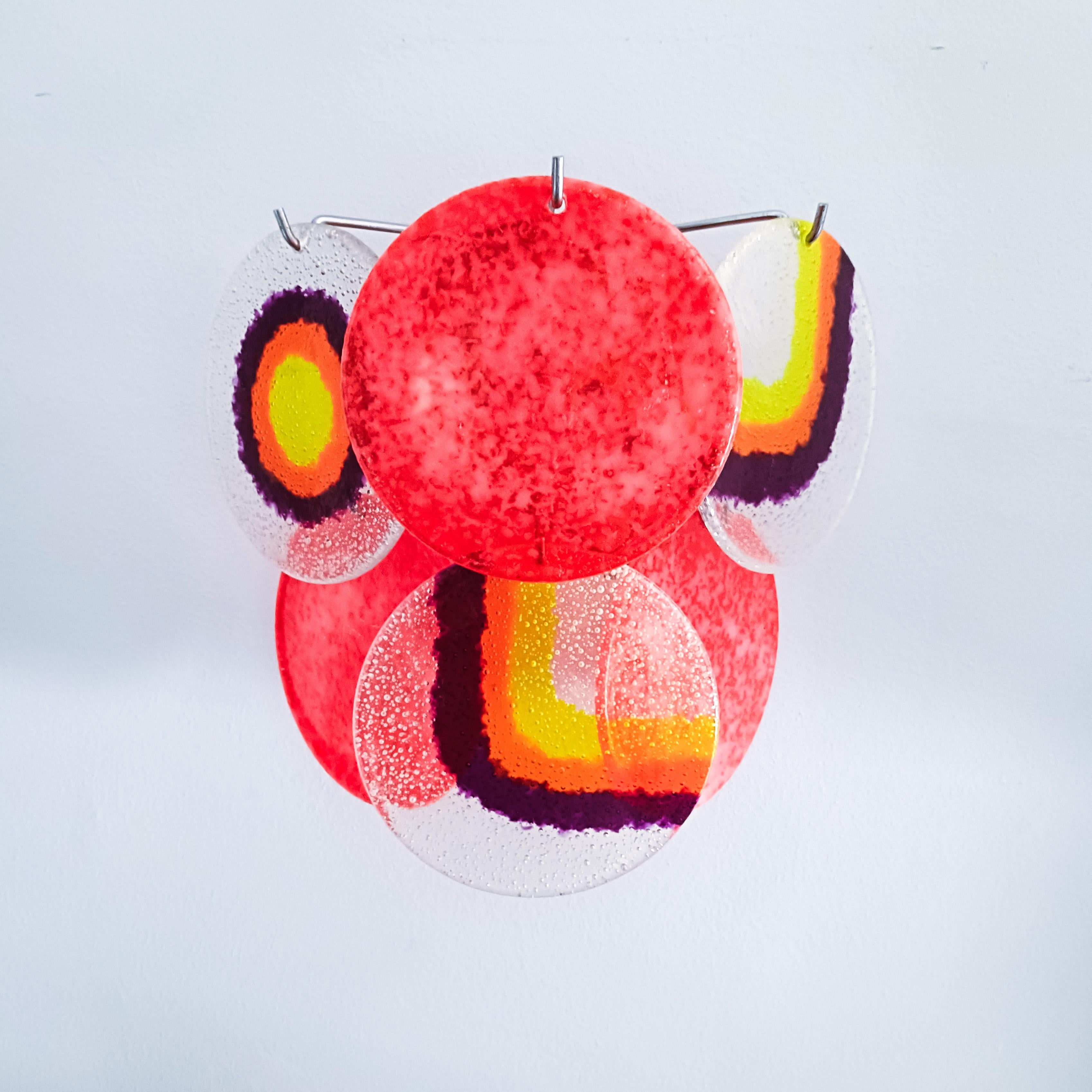 Set of 4 Italian wall lights by Targetti Sankey, 1970s. Each piece has a silver chromed metal structure where 6 acrylic or methacrylate discs with different motifs are held, combining yellow, orange, purple, magenta and transparent colors. Very