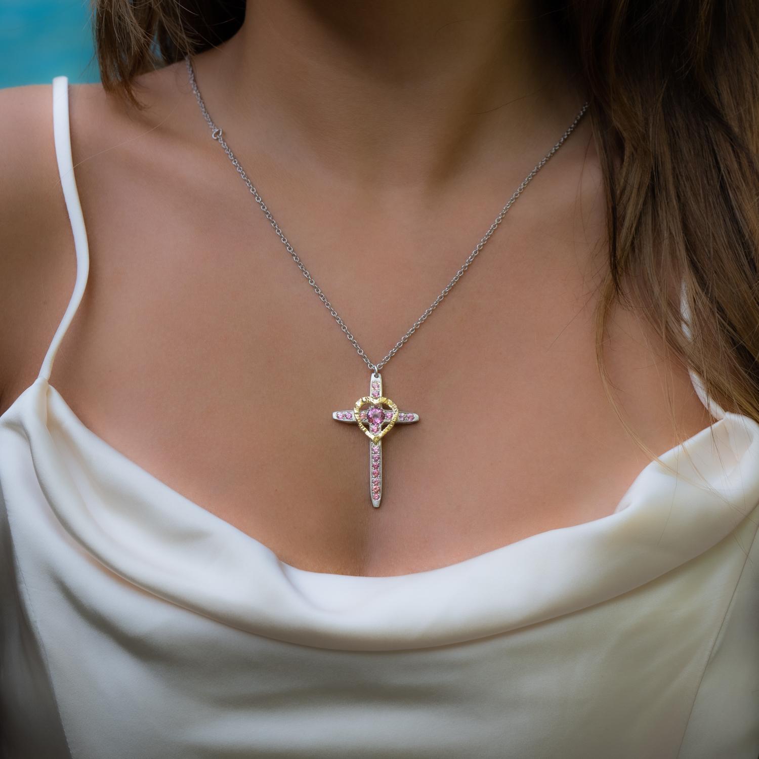 This elegant cross and heart necklace is a unique blend of traditional and modern design. The cross, a timeless symbol of faith and devotion, is adorned with beautiful pink topaz, adding a touch of color and elegance to the piece. The pink topaz