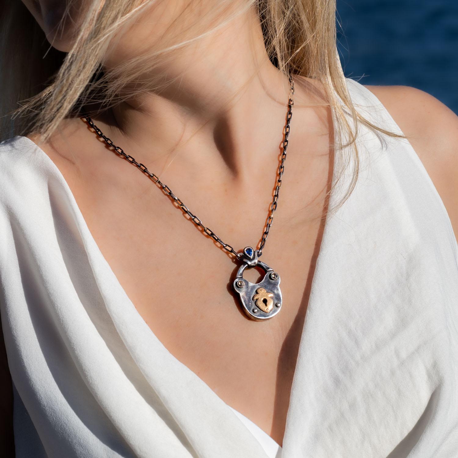 This charming 18K gold and oxidized sterling silver lock pendant necklace has an antique look dating back to medieval ages. The pendant is set with two rosecut diamonds and a pear shaped blue sapphire.

Lock necklace serial number T237
brown rosecut